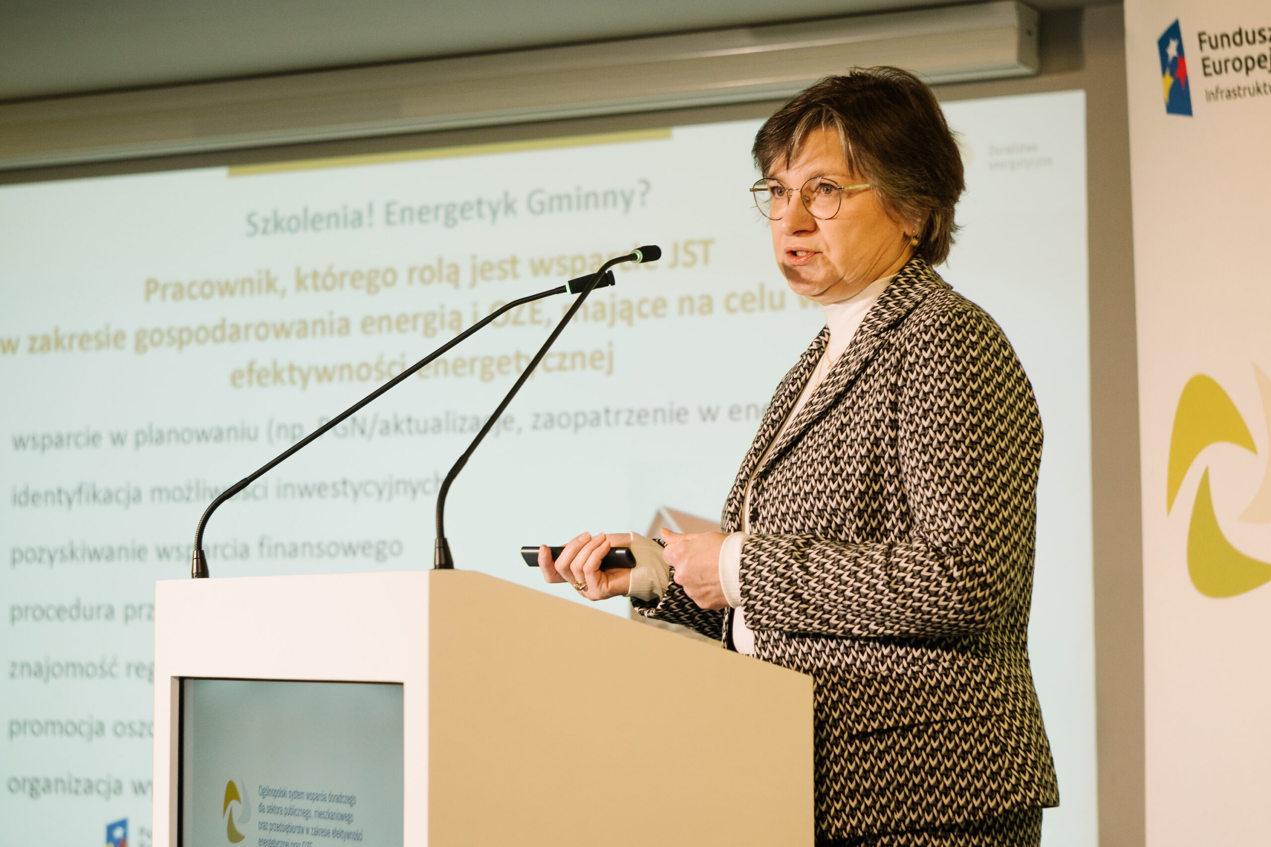 1 osoba stoi przy mównicy i przemawia na konferencji.