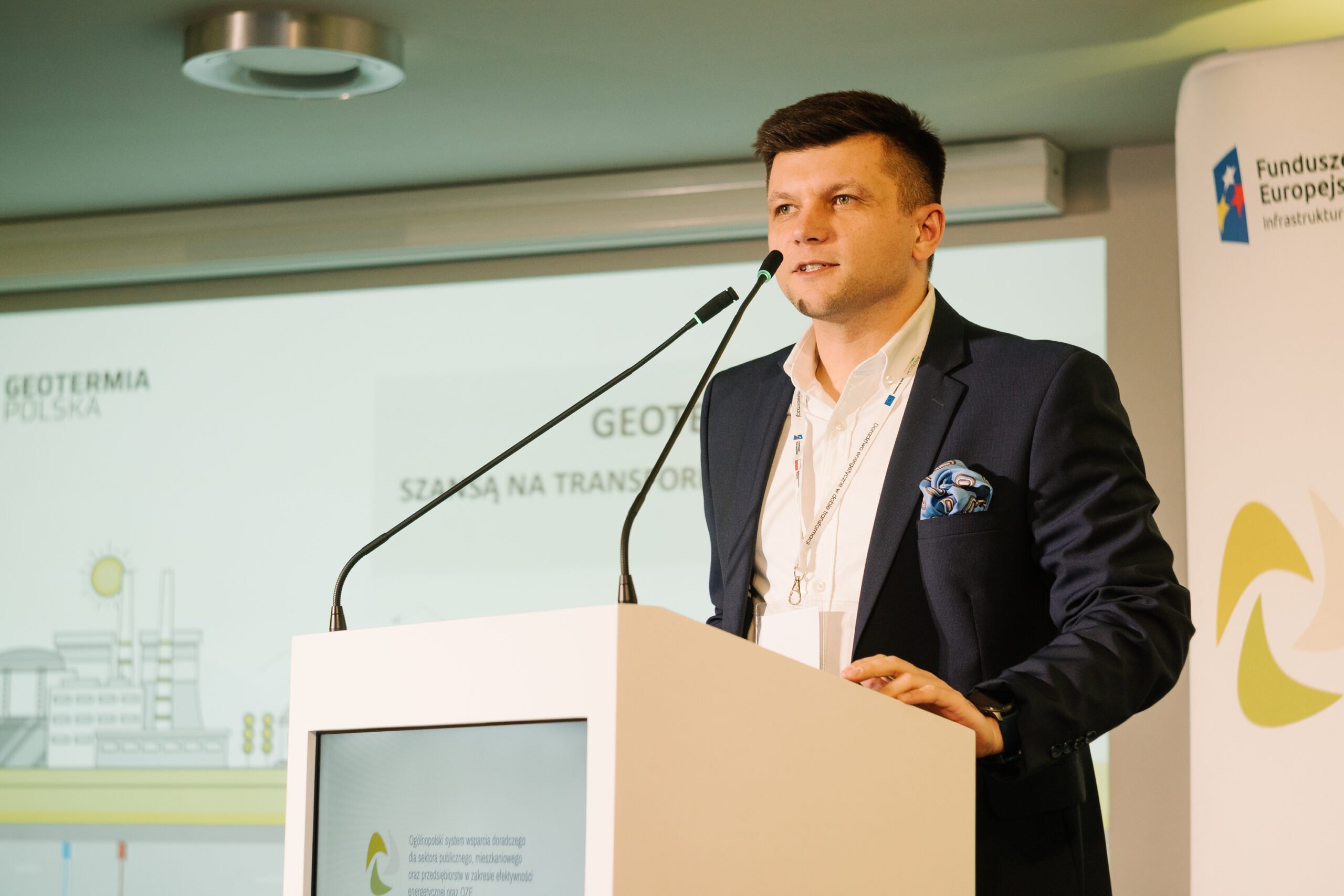 1 osoba stoi przy mównicy i przemawia na konferencji.