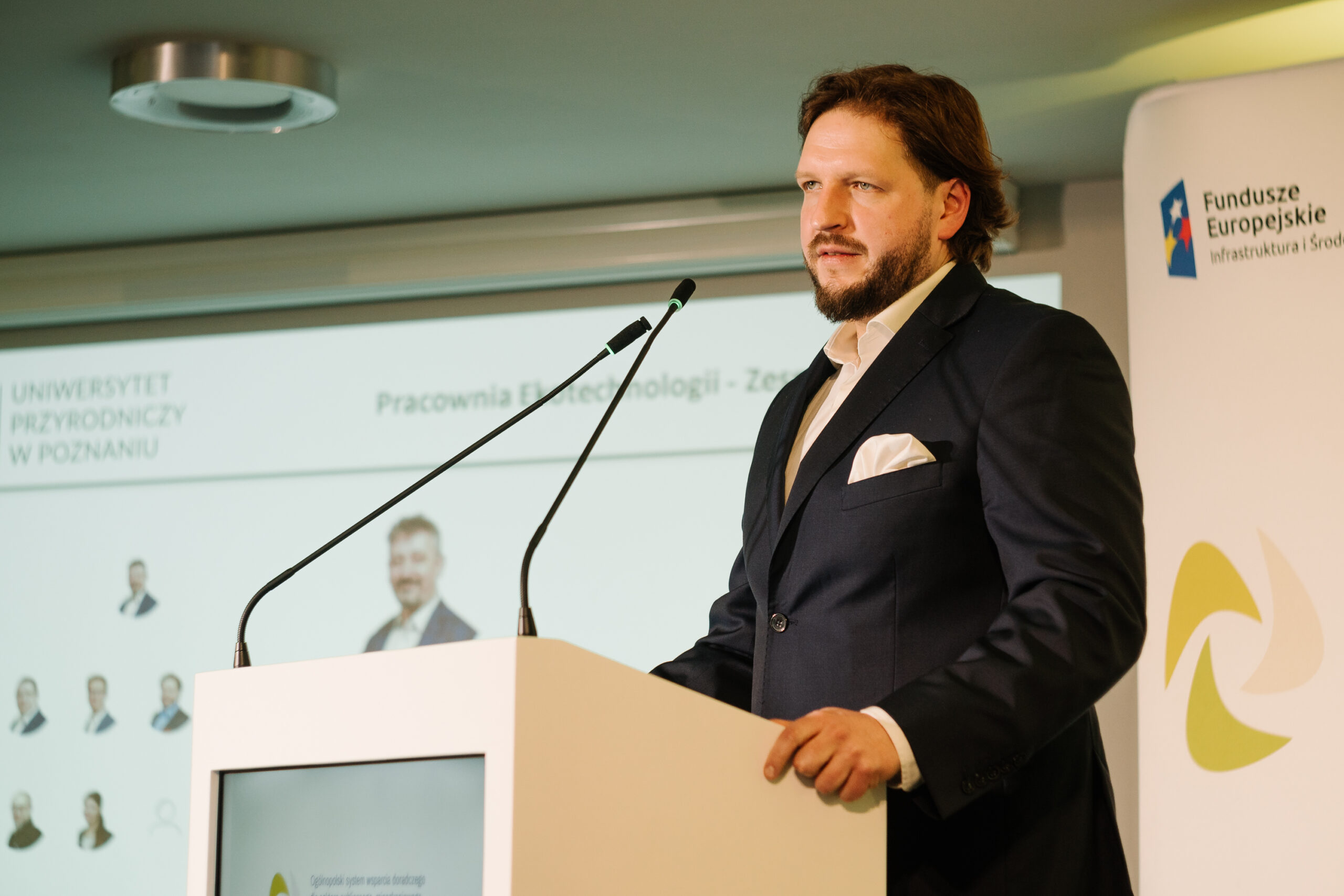 1 osoba stoi przy mównicy i przemawia na konferencji.