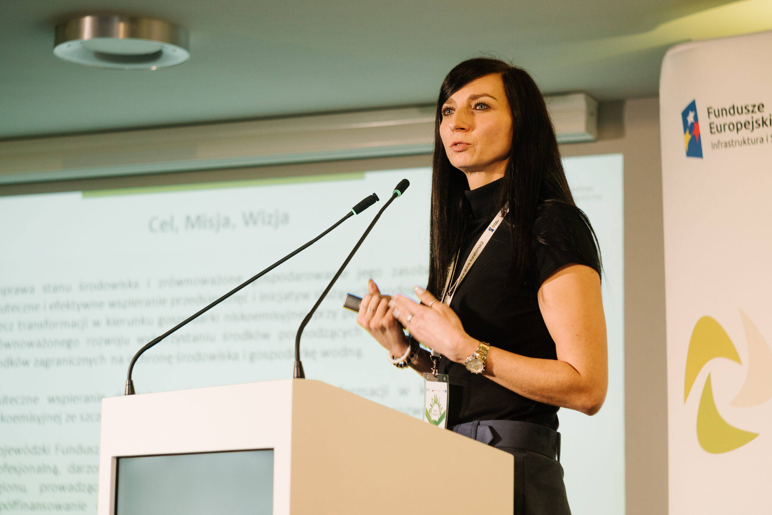 1 osoba stoi przy mównicy i przemawia na konferencji.