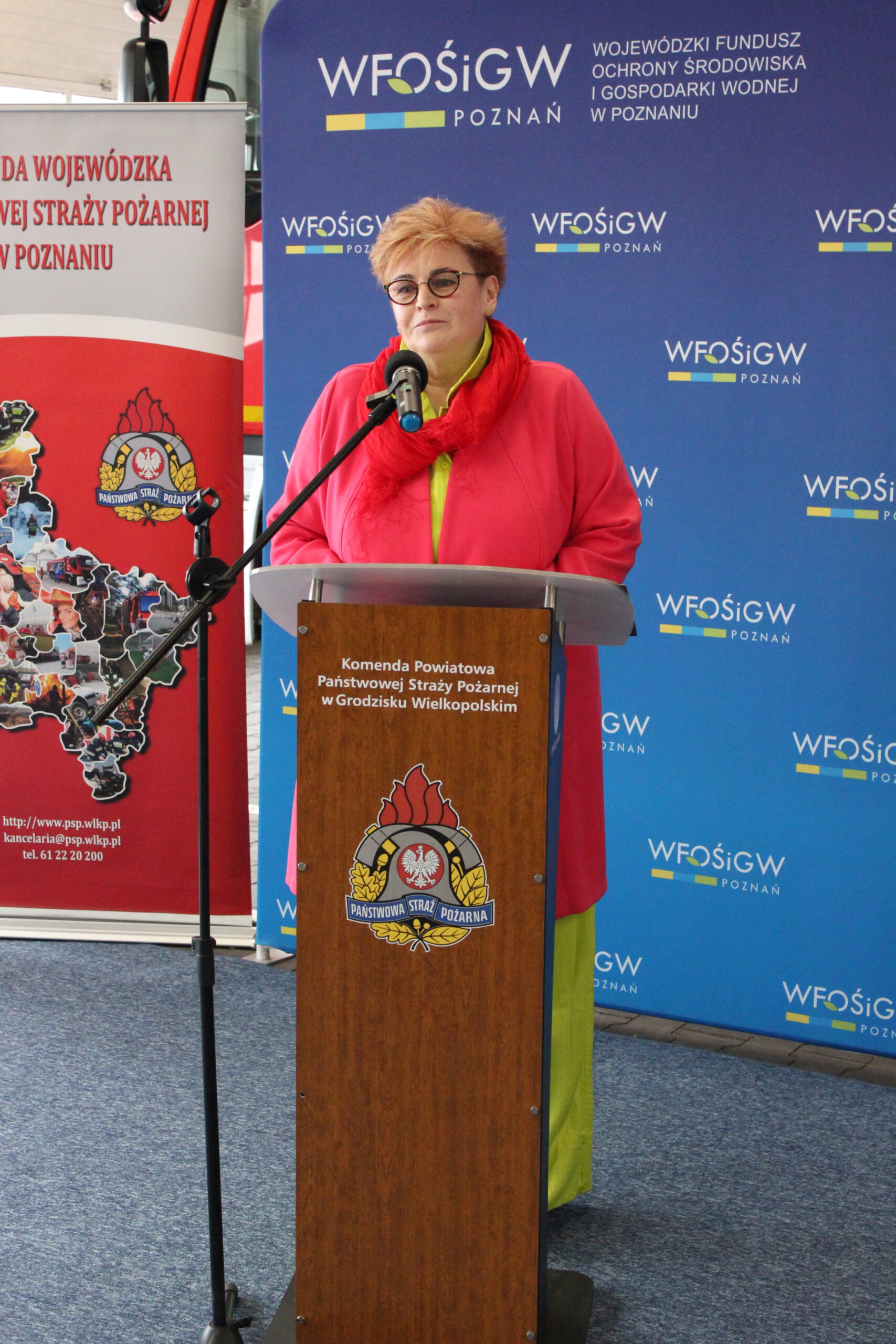 1 osoba stoi przy mównicy i przemawia.