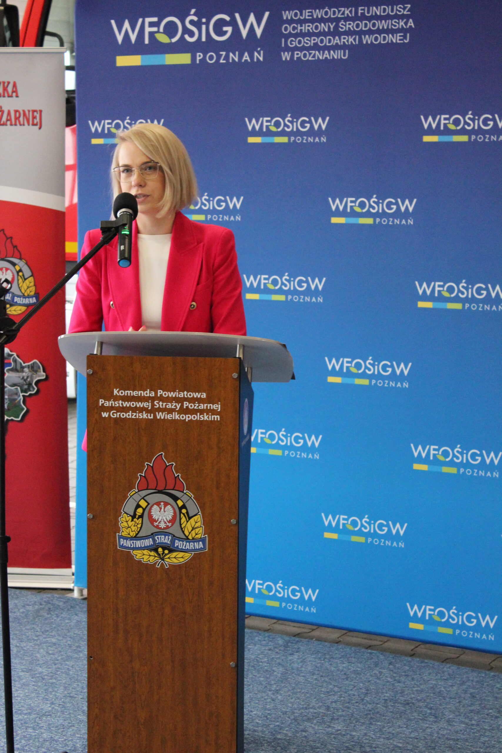 1 osoba stoi przy mównicy i przemawia.