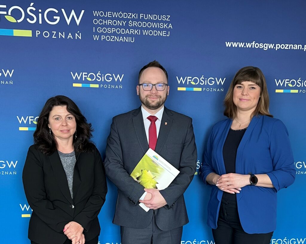 3 osoby stoją na tle ściany.