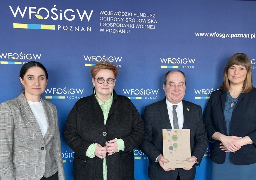 4 osoby stoją na tle ściany.