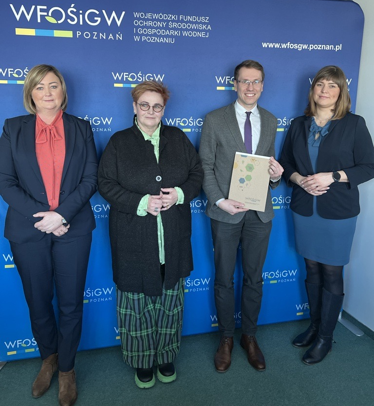 4 osoby stoją na tle ściany.