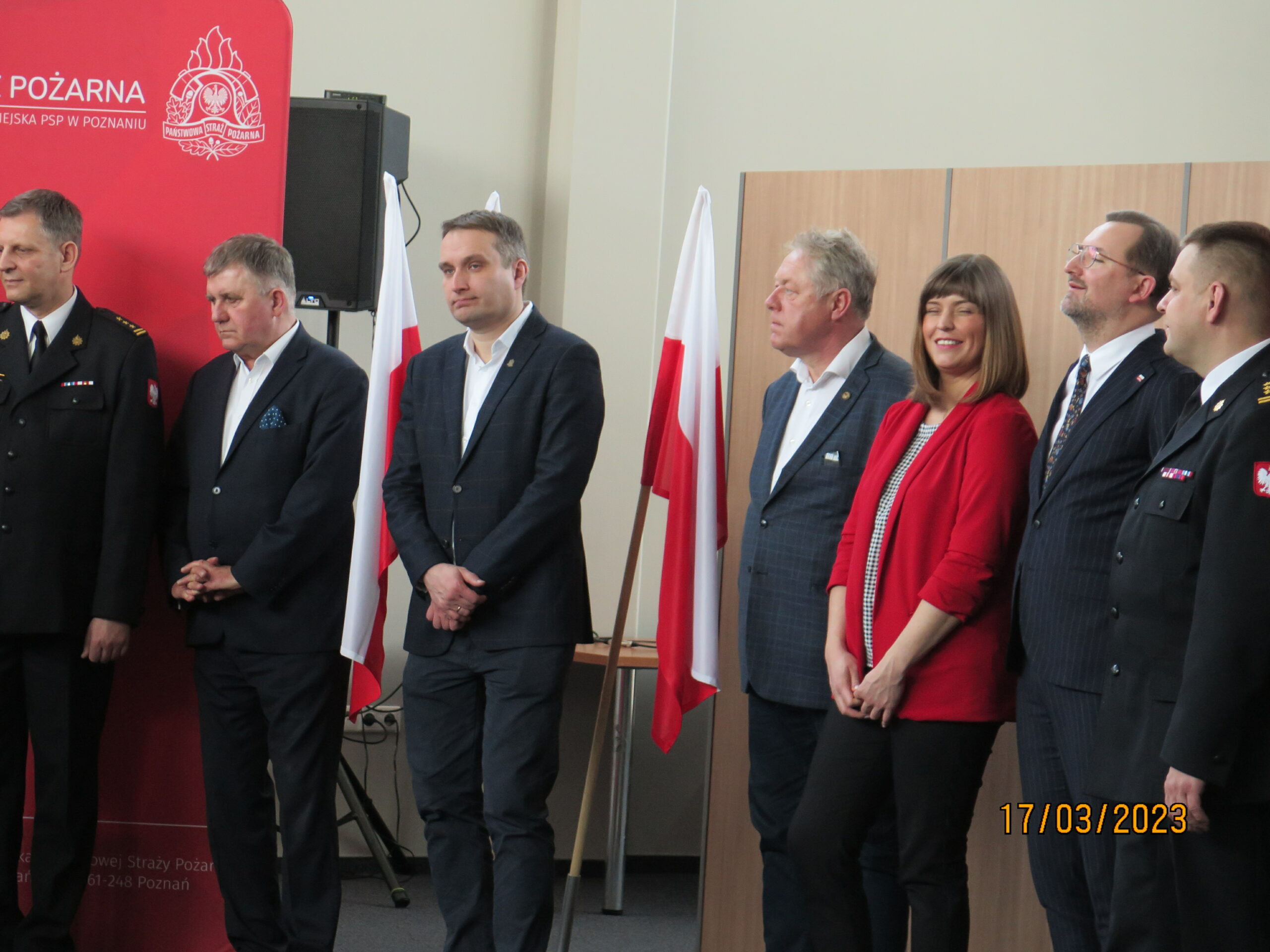 5 osób stoi i słucha.