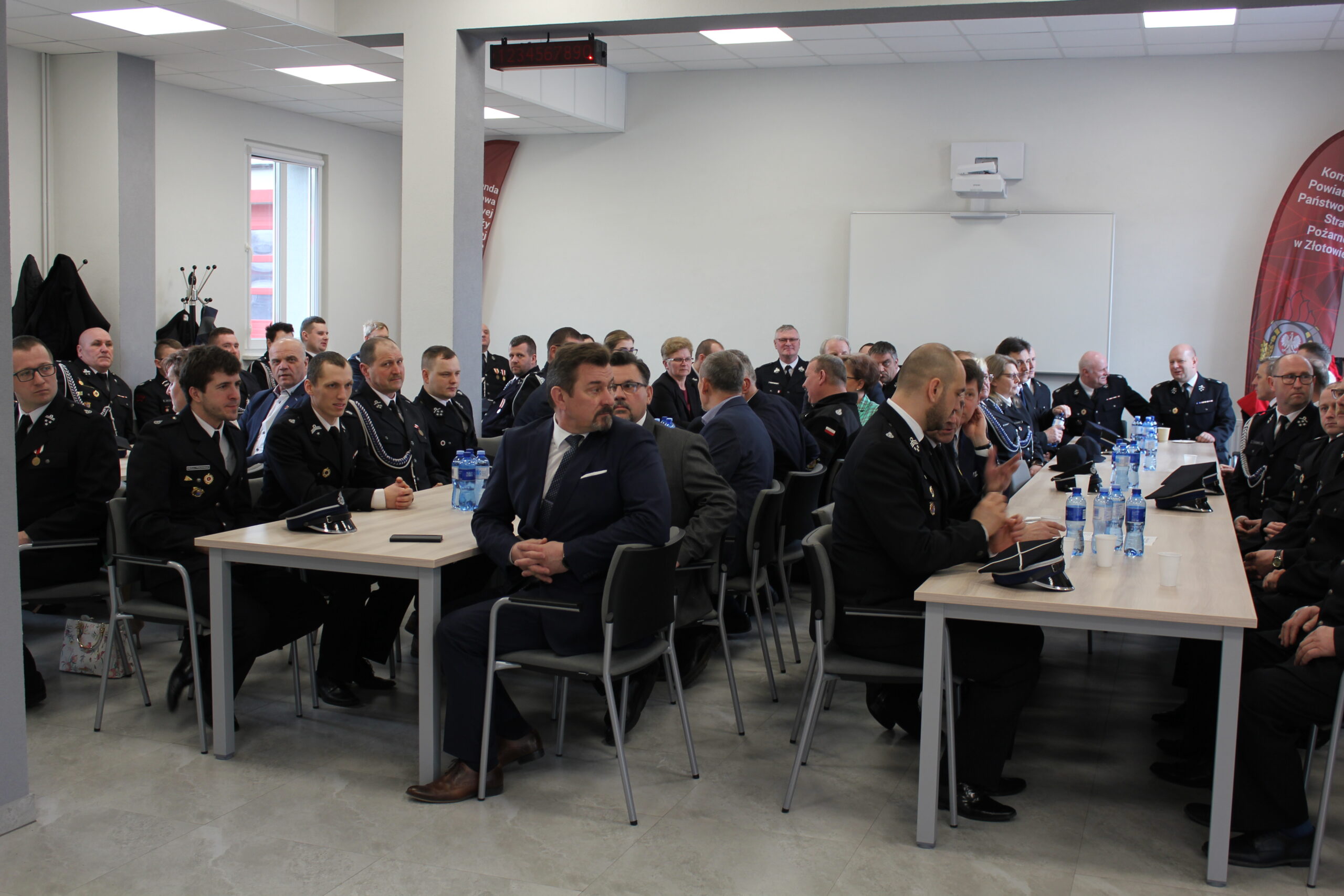 Grupa strażaków - ochotników siedzi na sali.