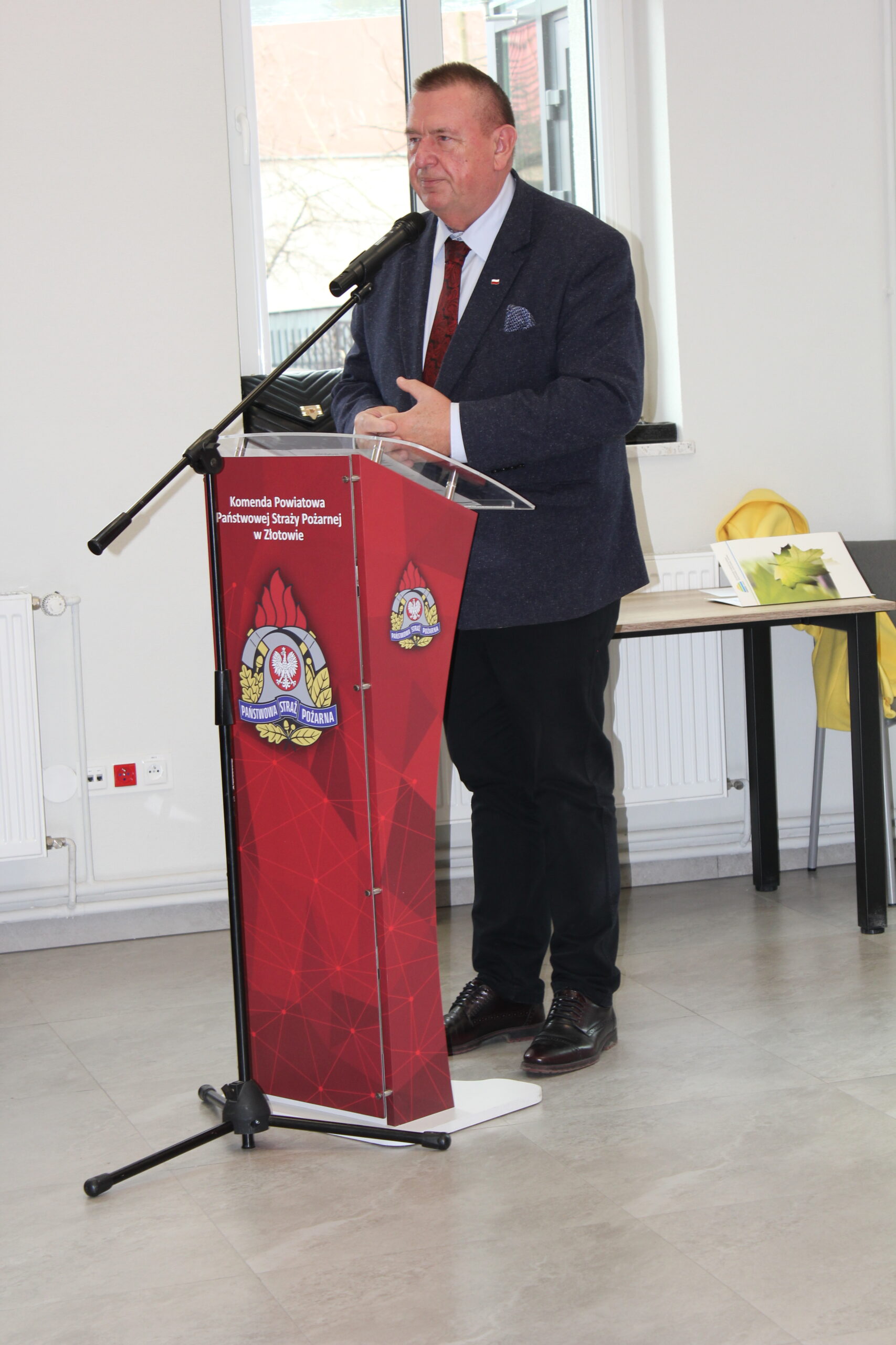 1 osoba stoi przy mównicy i przemawia.