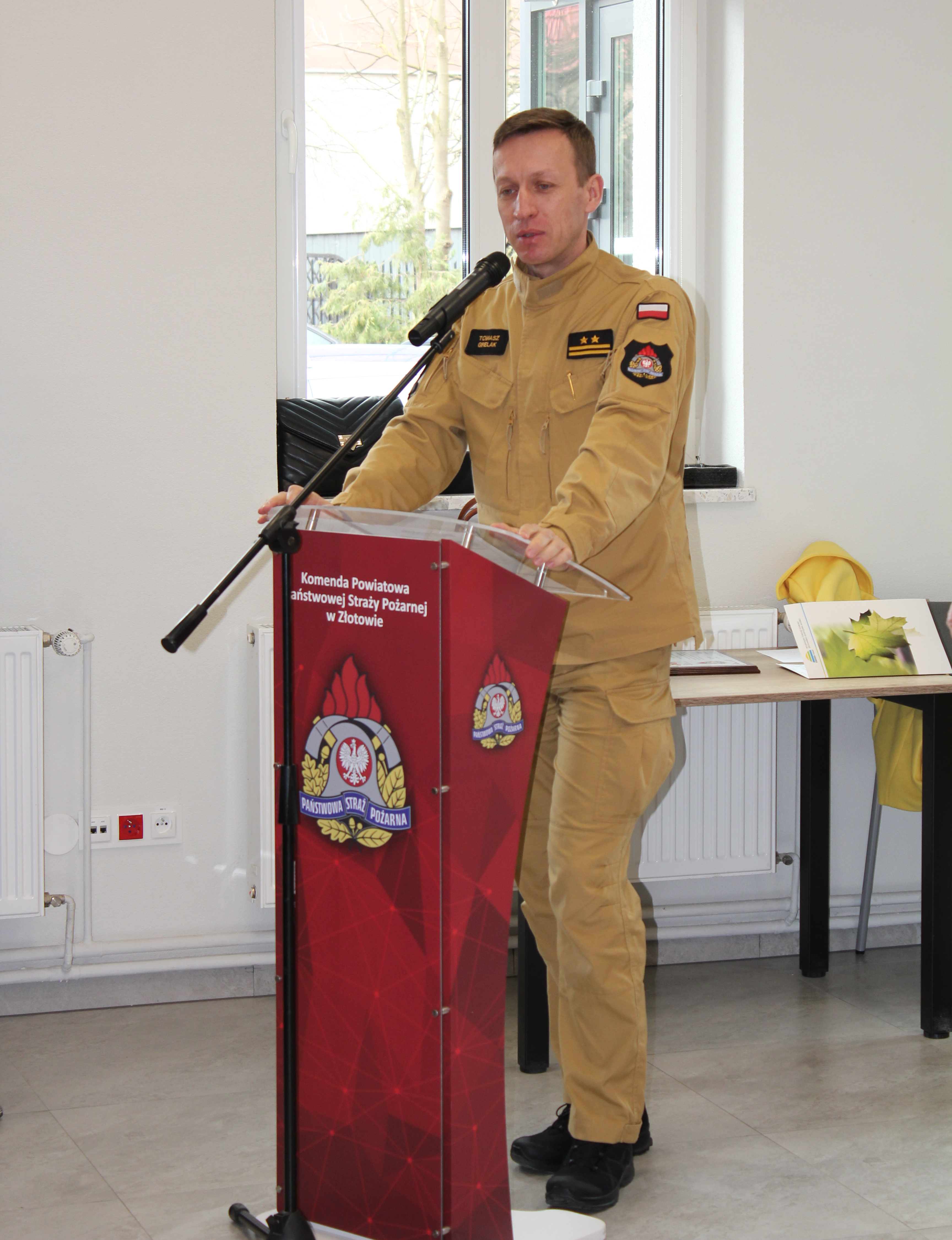 1 osoba stoi przy mównicy i przemawia.