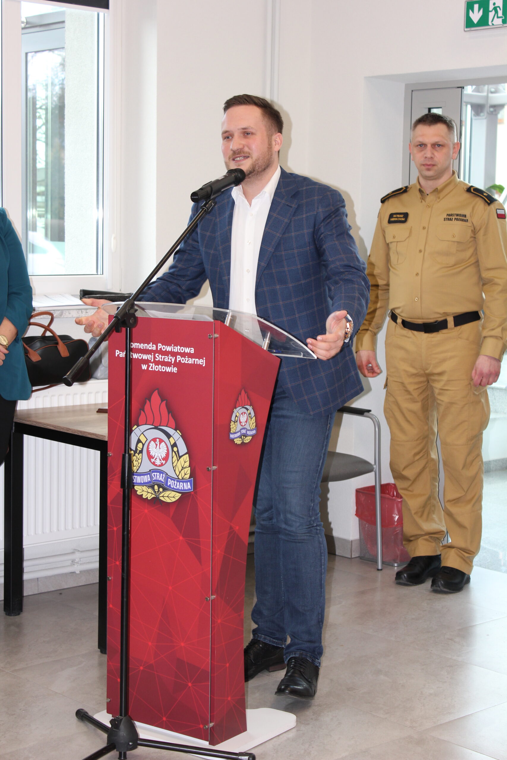 1 osoba stoi przy mównicy i przemawia.