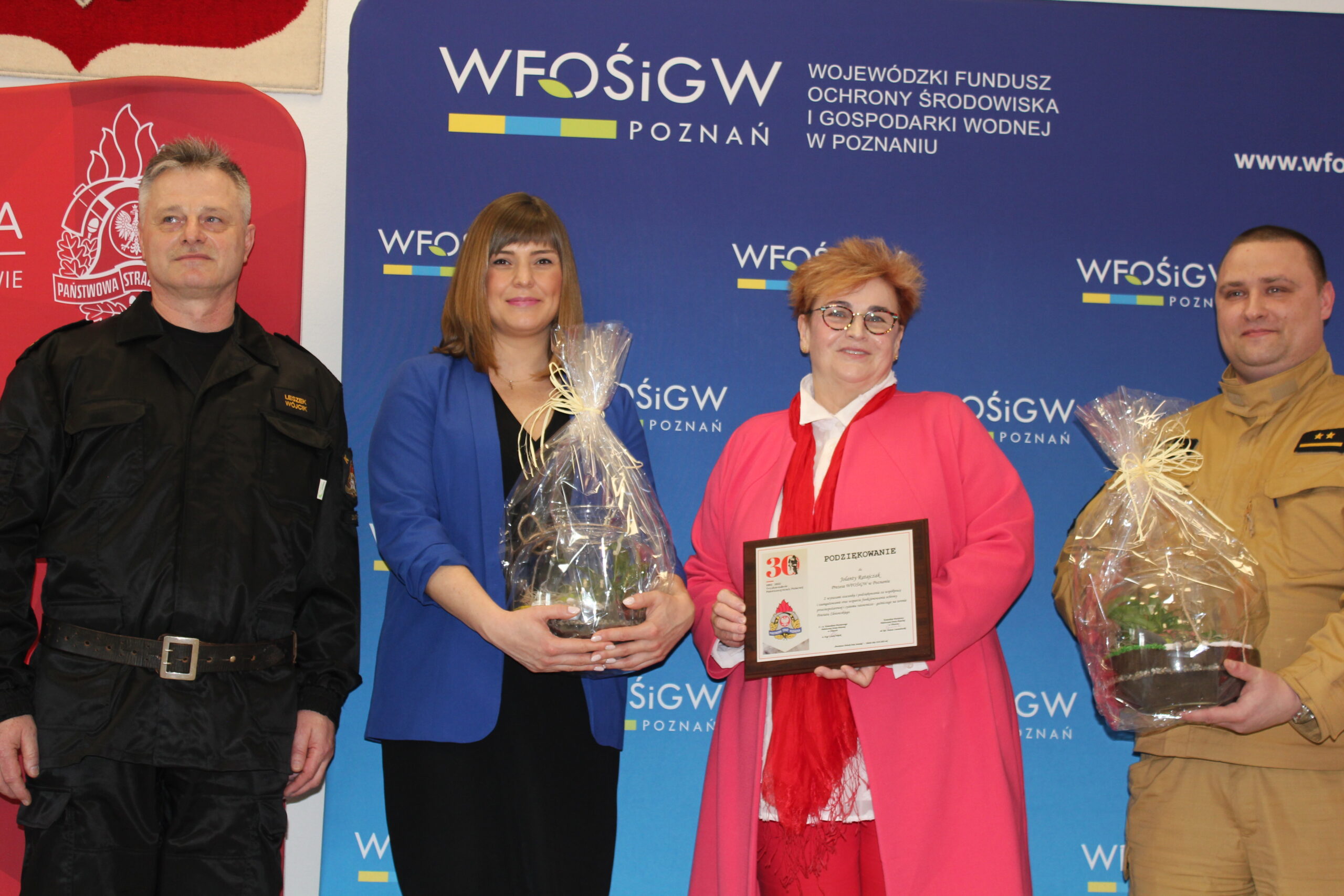 4 osoby stoją na tle ściany.