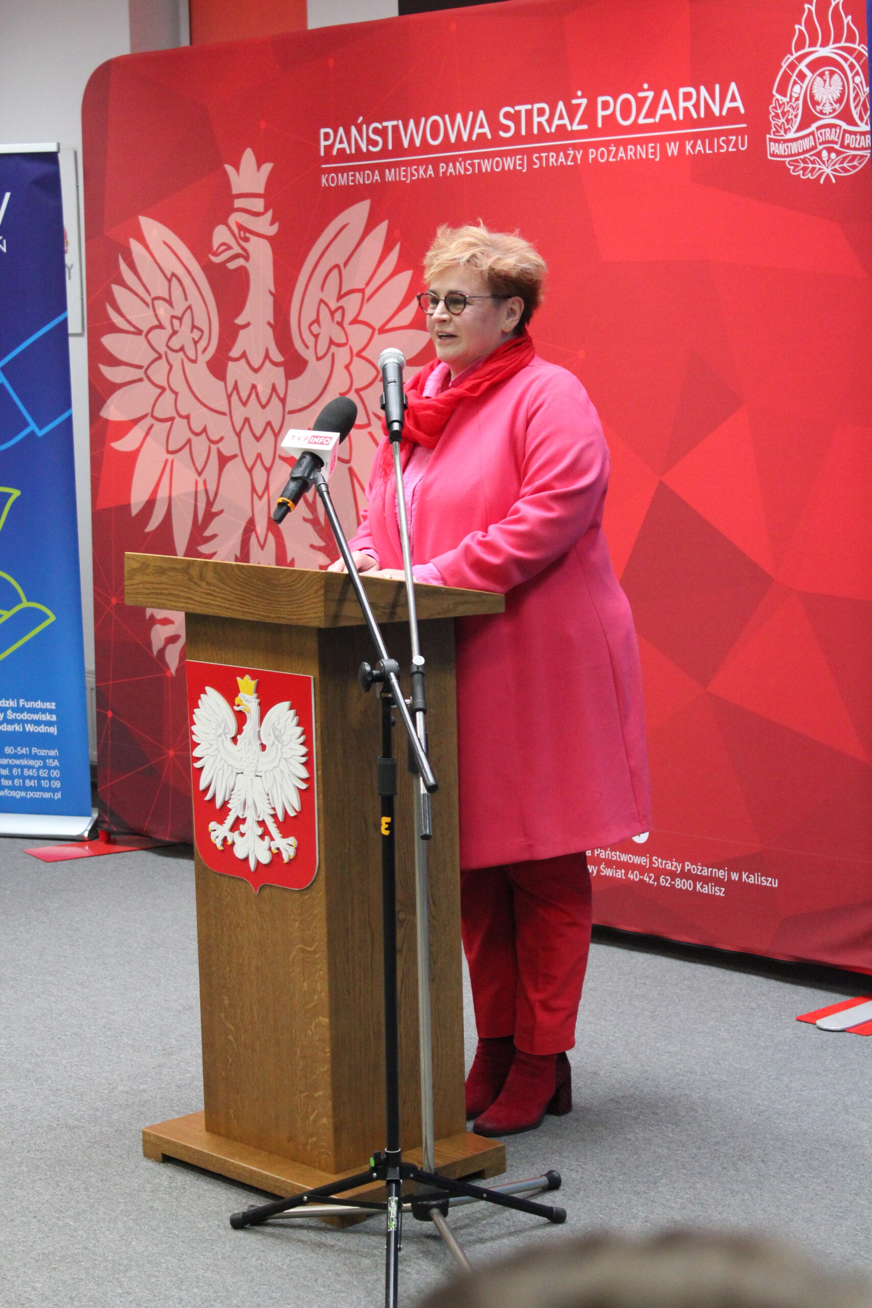 1 osoba stoi przy mównicy i przemawia.