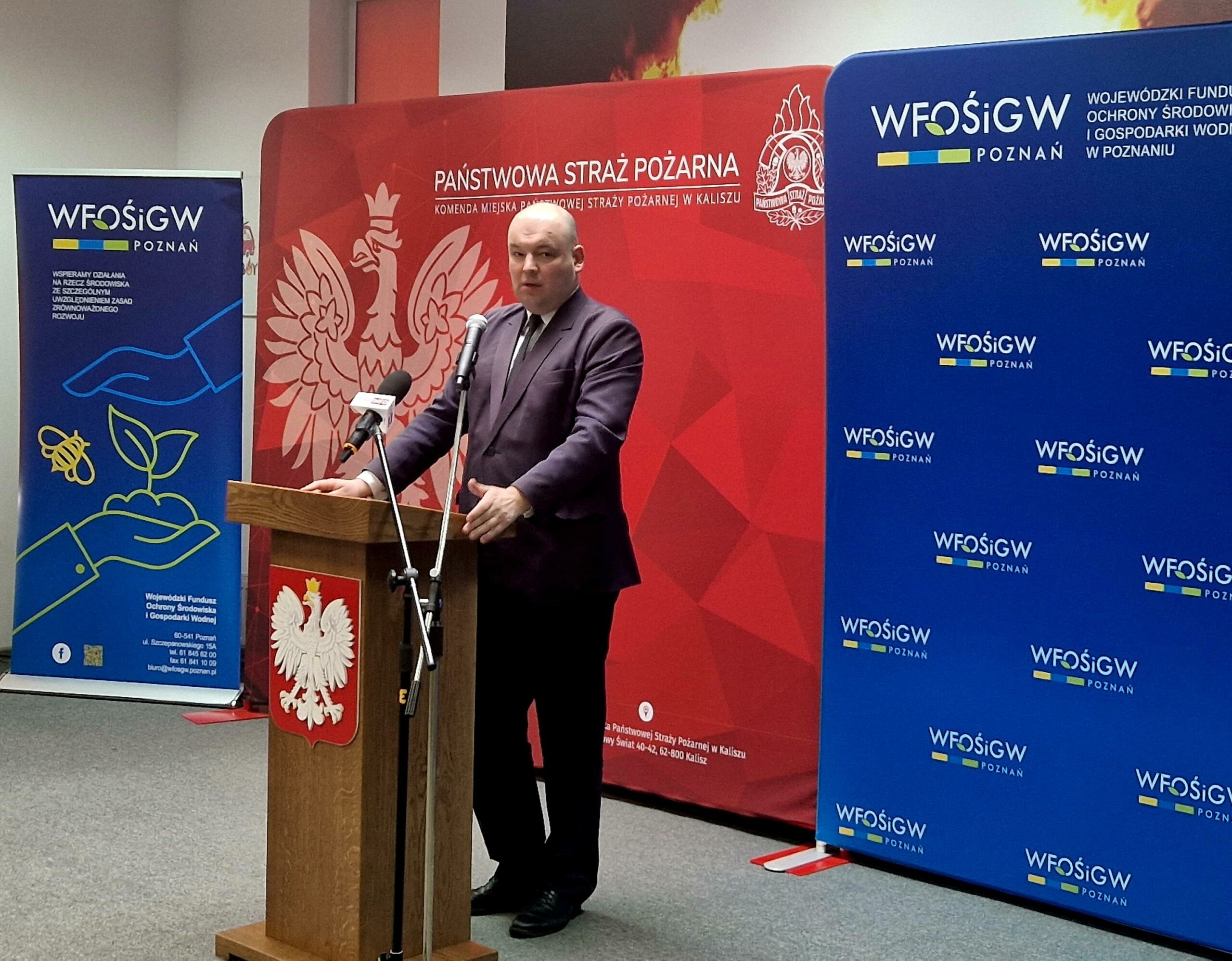 1 osoba stoi przy mównicy i przemawia.