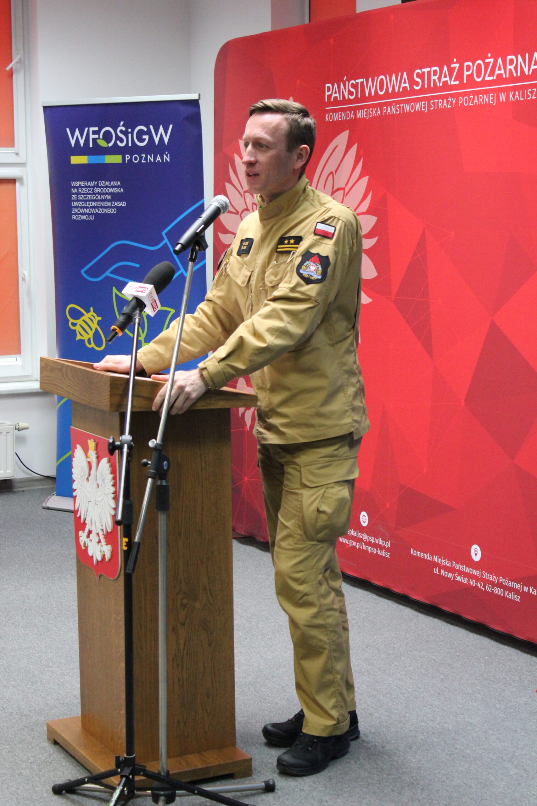 1 osoba stoi przy mównicy i przemawia.