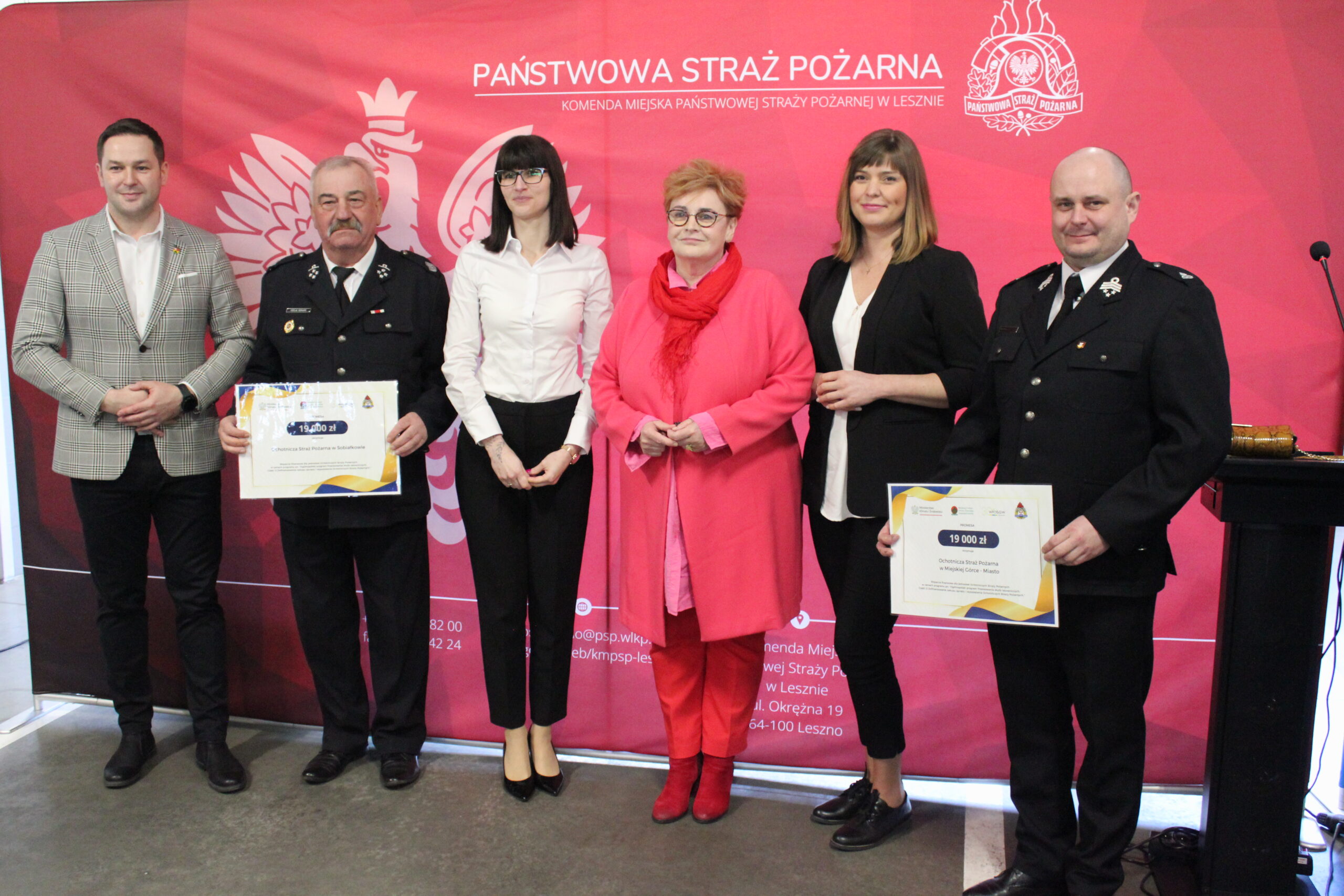 6 osób stoi na tle ścianek reklamowych.