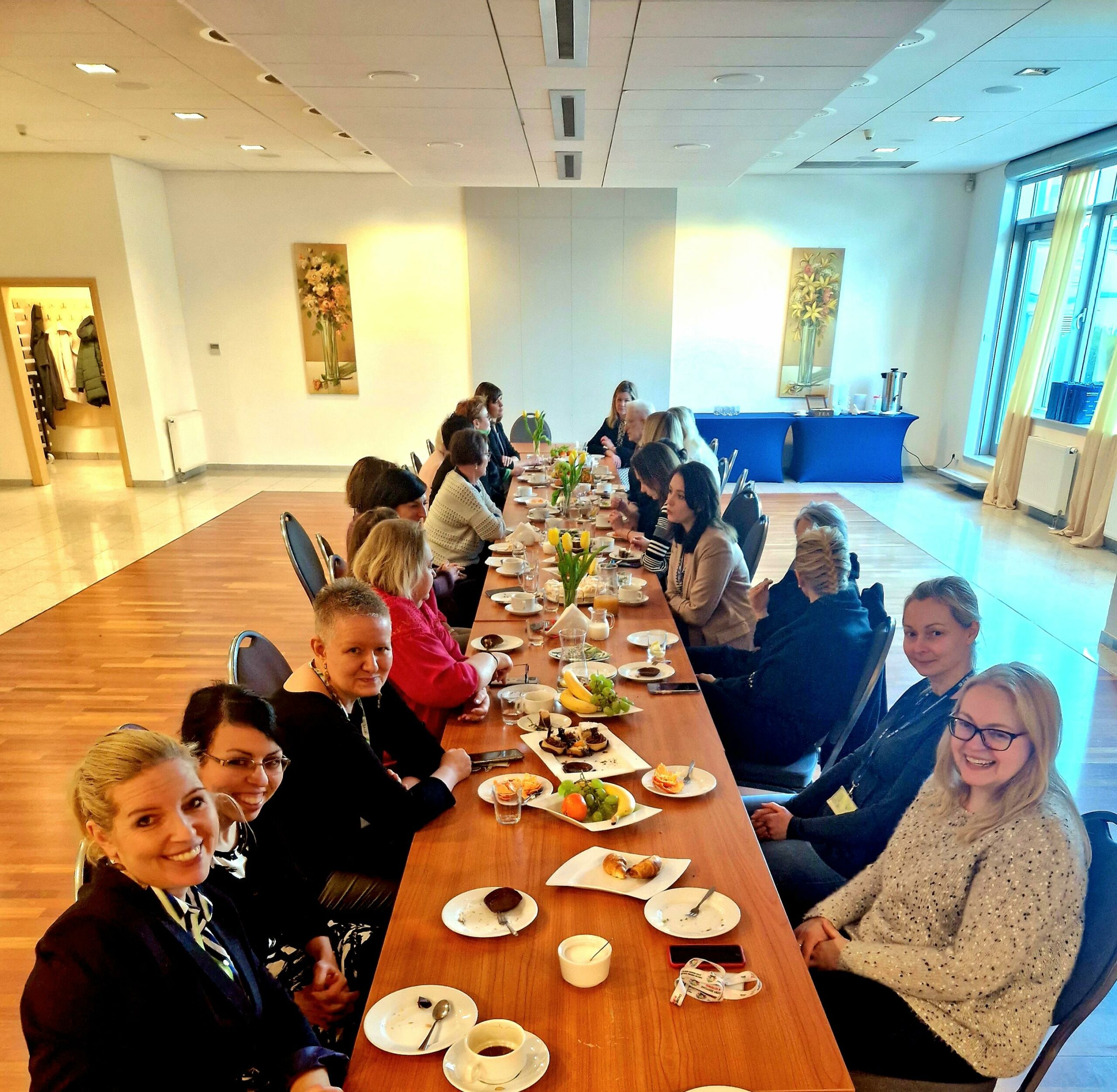 Grupa osób siedzi przy długim stole.