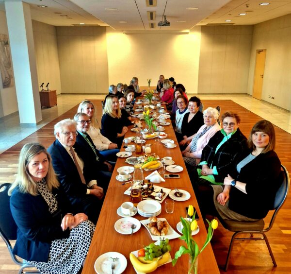 Grupa osób siedzi przy długim stole.