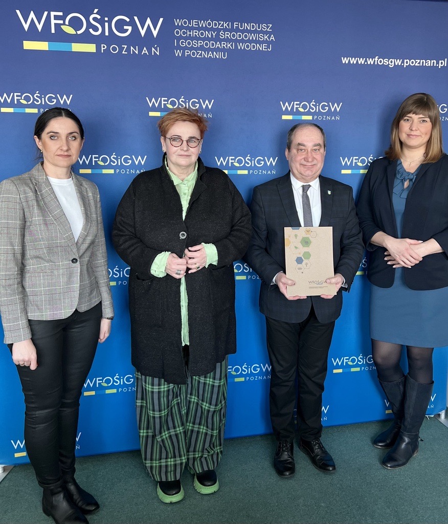 4 osoby stoją na tle ściany.