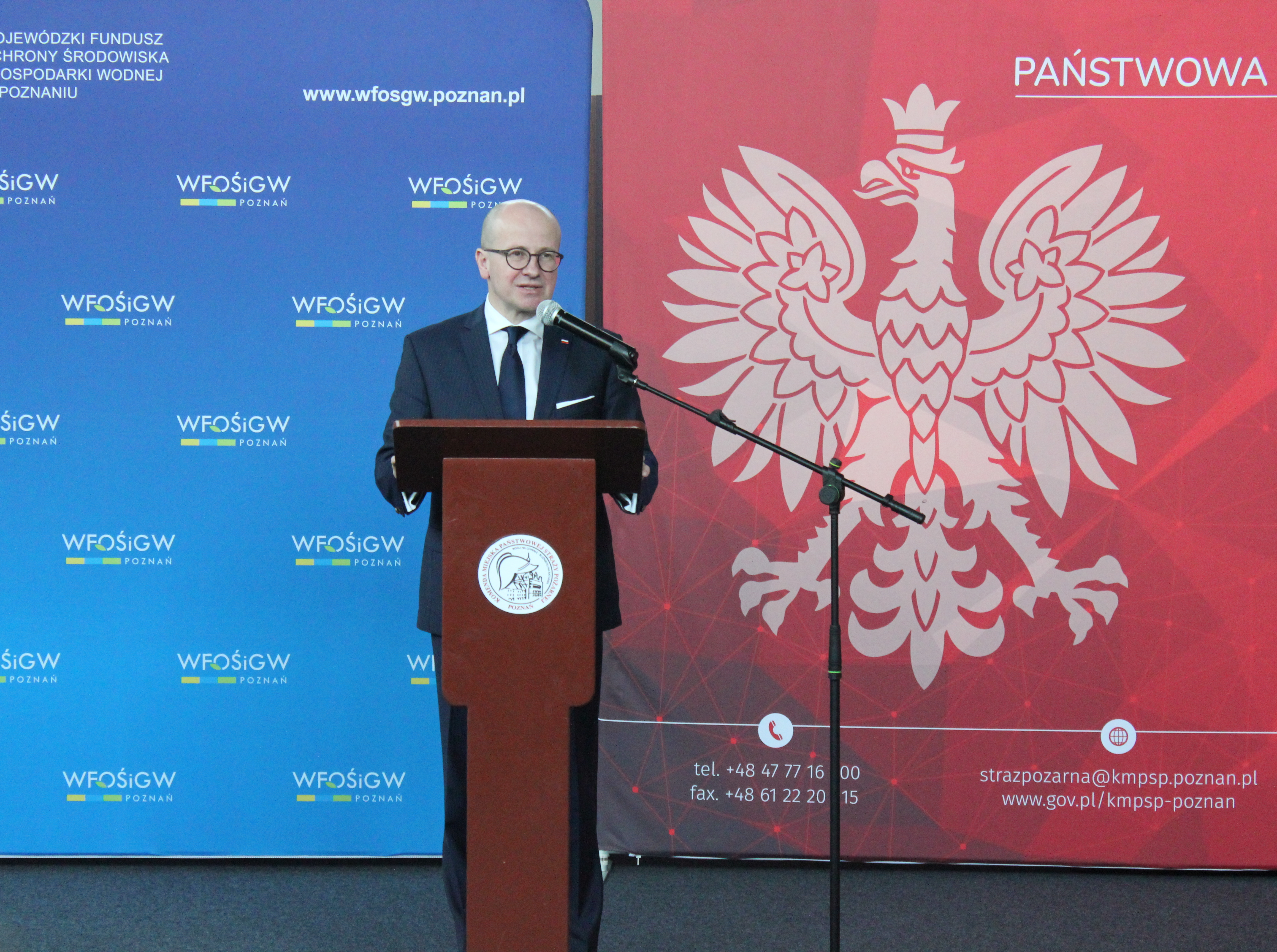 Jedna osoba stoi przy mównicy i przemawia.