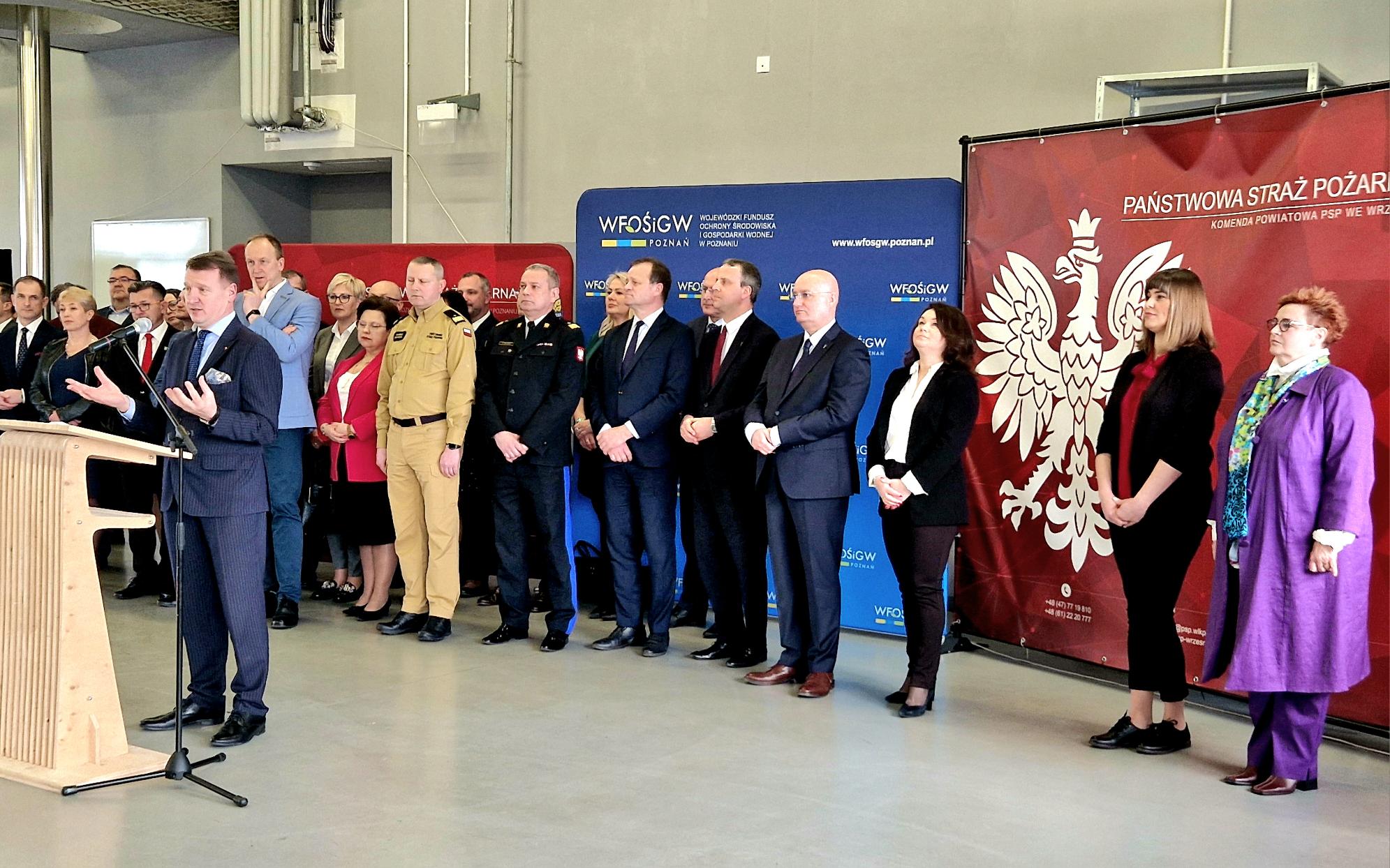 1 osoba stoi przy mównicy i przemawia.