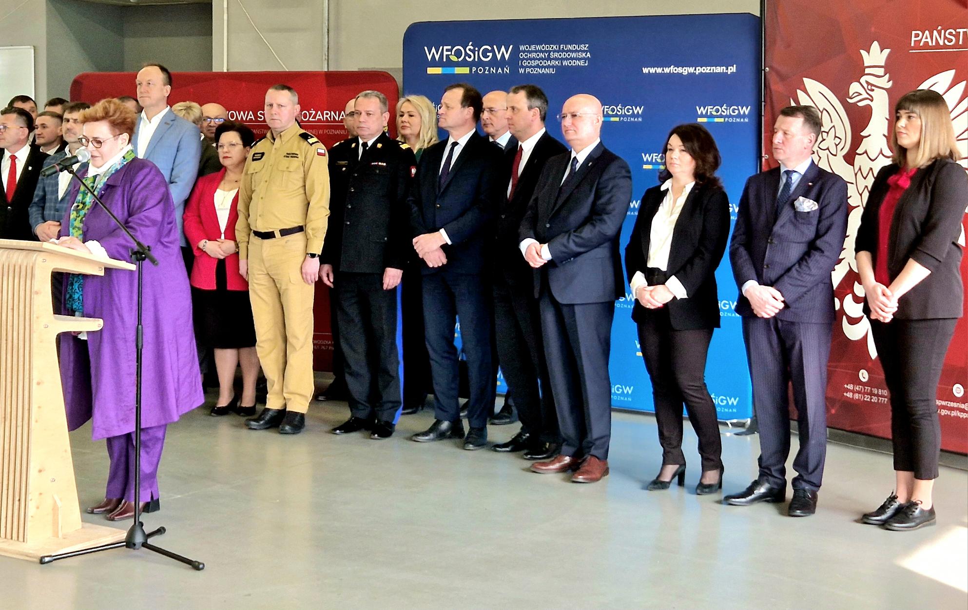 1 osoba stoi przy mównicy i przemawia.