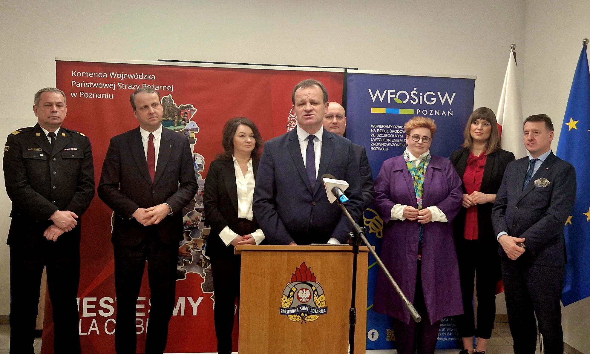 1 osoba stoi przy mównicy i przemawia.