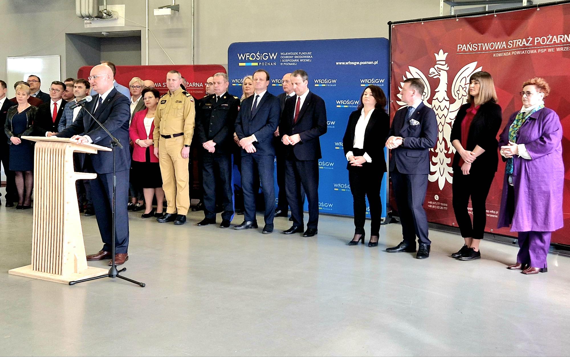 1 osoba stoi przy mównicy i przemawia.