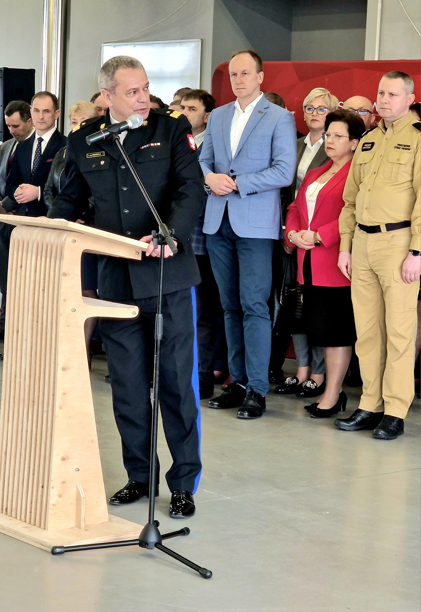 1 osoba stoi przy mównicy i przemawia.