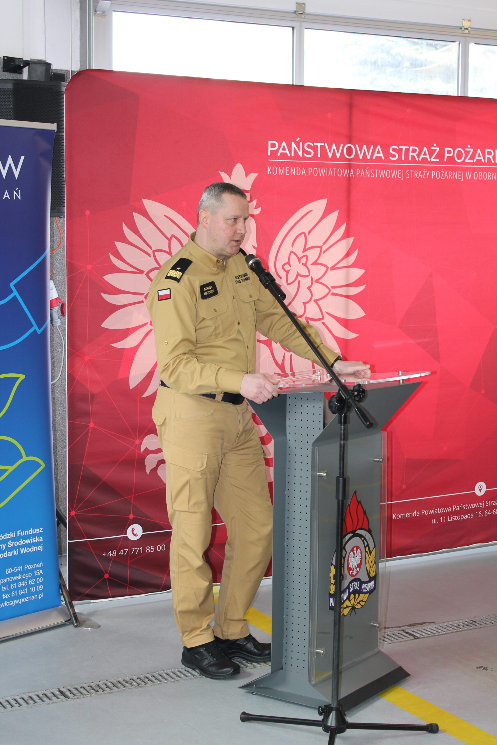 1 osoba stoi przy mównicy i przemawia.