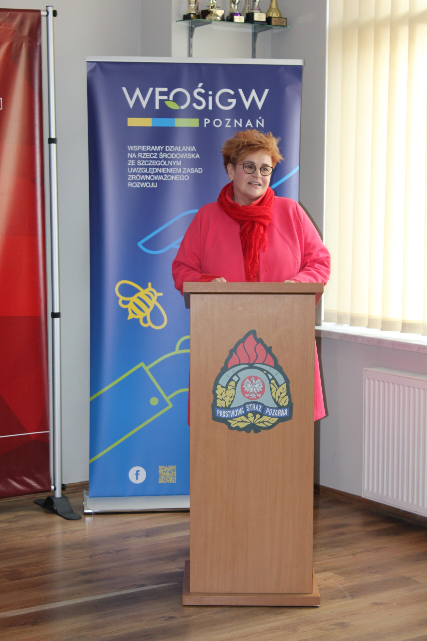 1 osoba stoi przy mównicy i przemawia.