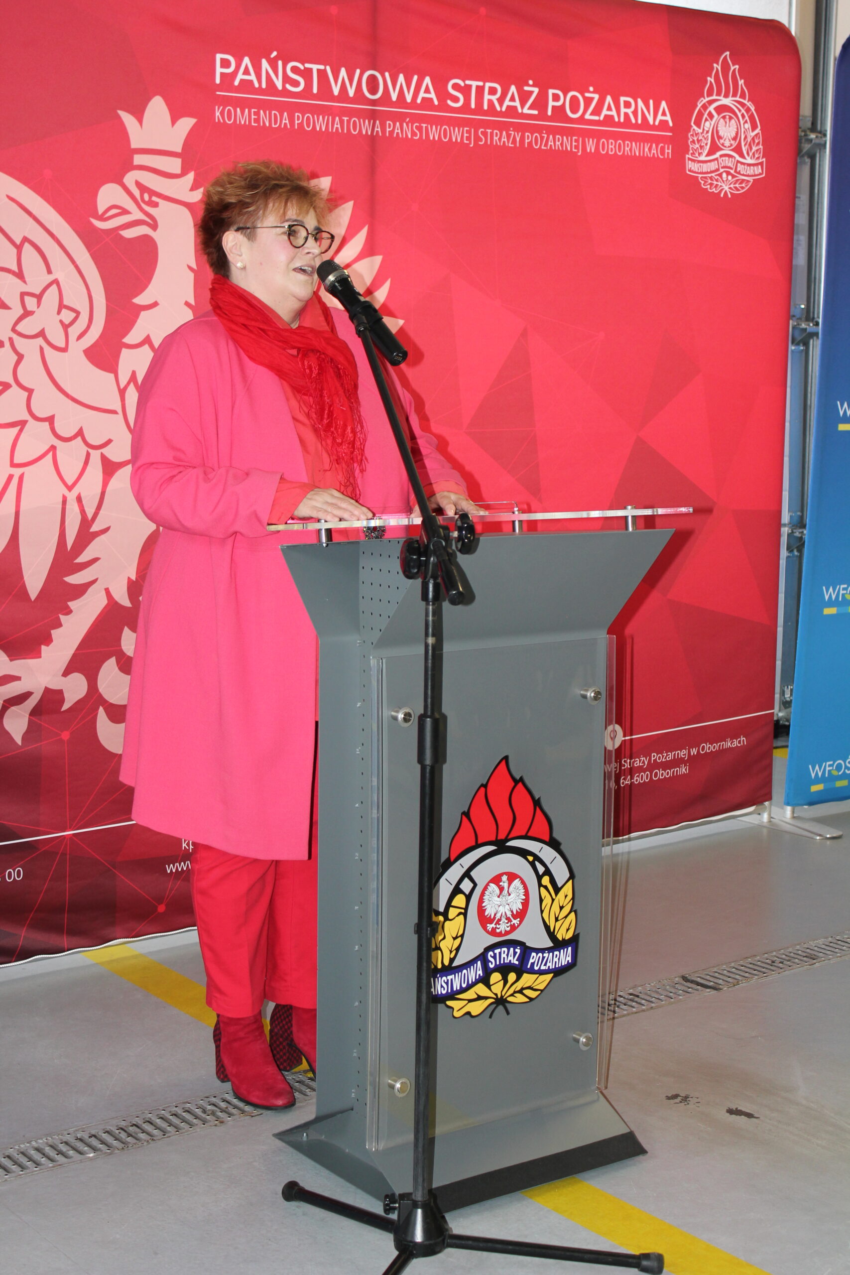 1 osoba stoi przy mównicy i przemawia.