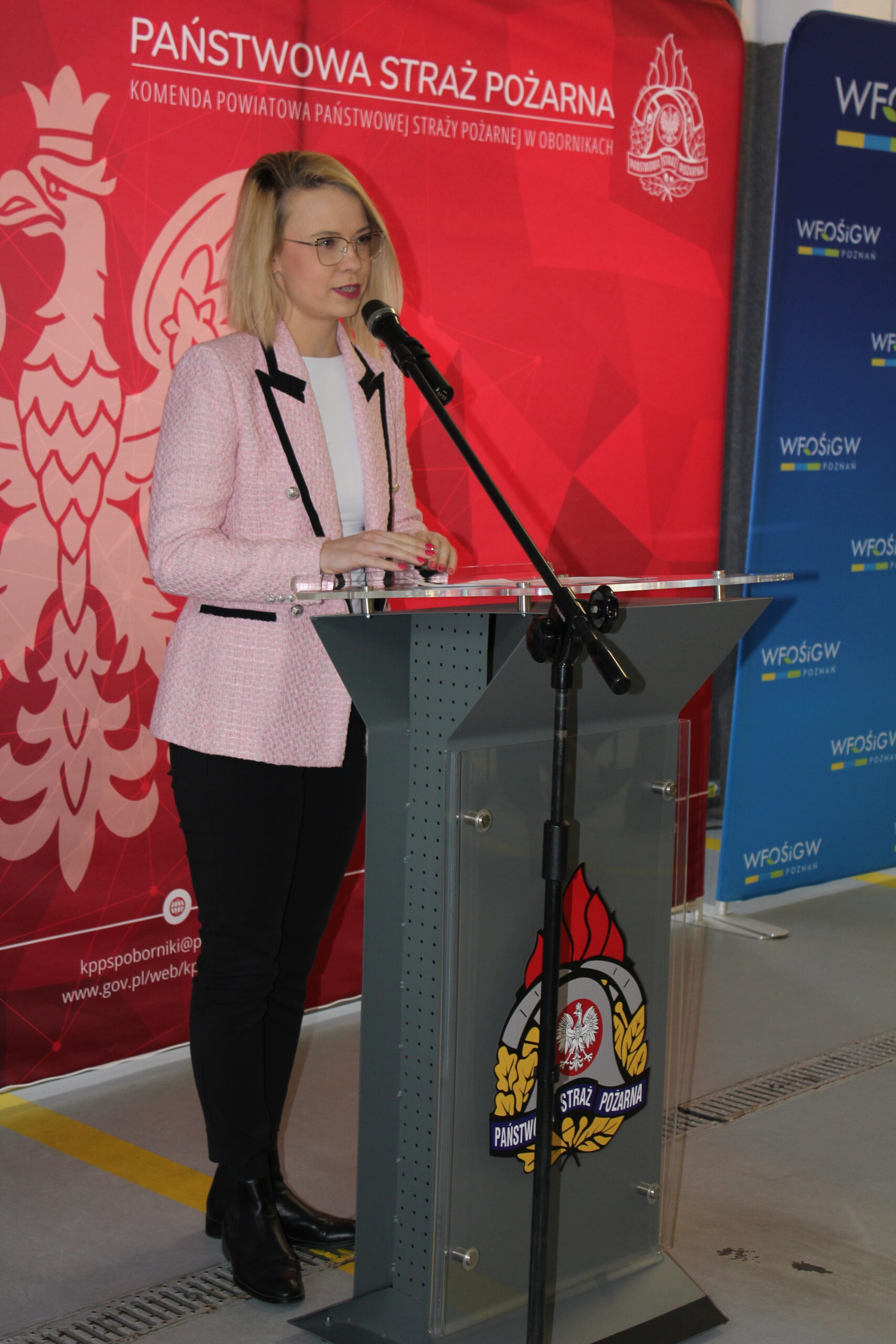 1 osoba stoi przy mównicy i przemawia.