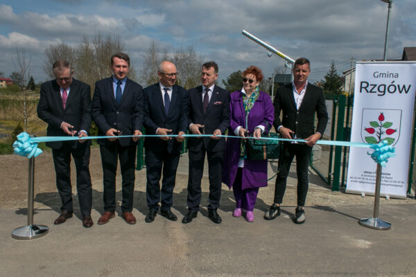 6 osób stoi na świeżym powietrzu i przecina wstęgę.