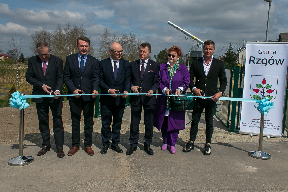 6 osób stoi na świeżym powietrzu i przecina wstęgę.