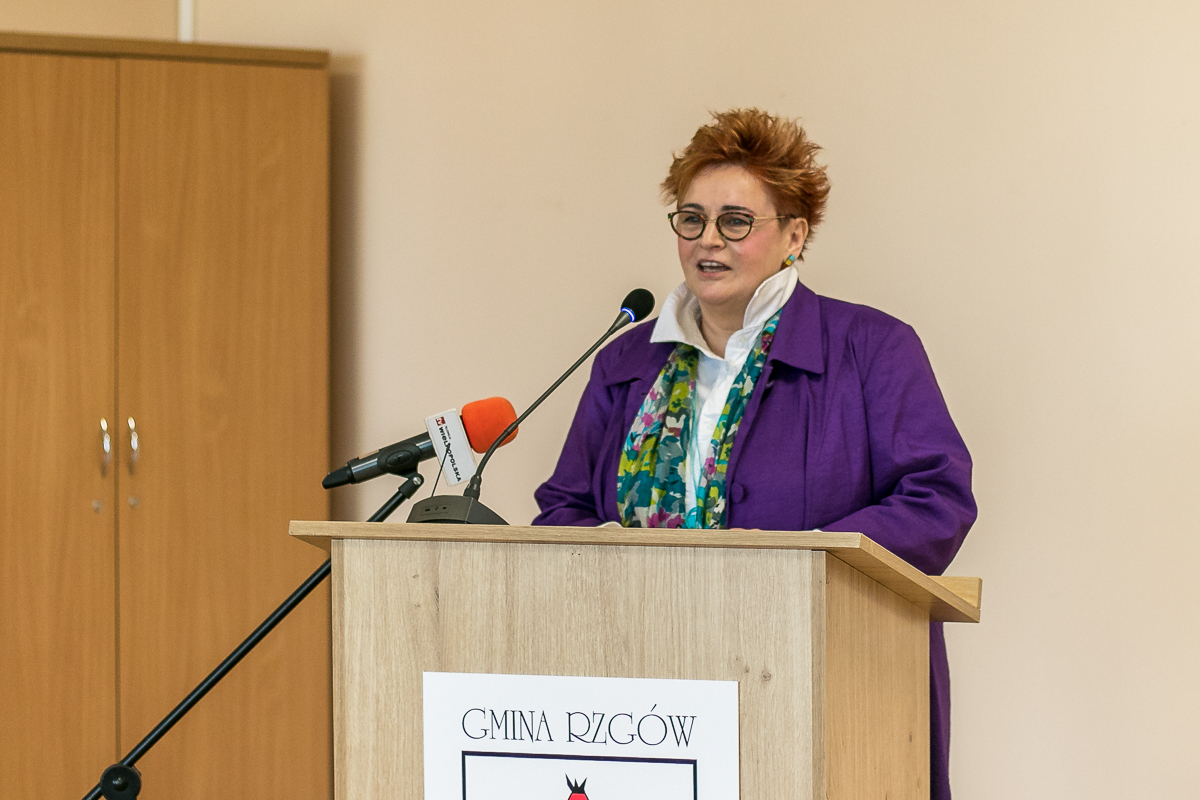 1 osoba stoi przy mównicy i przemawia.