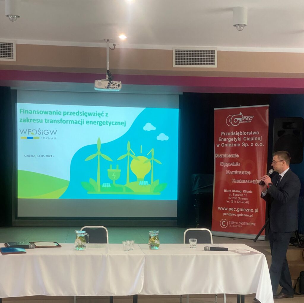 1 osoba stoi na tle ściany z projektorem i prezentuje.