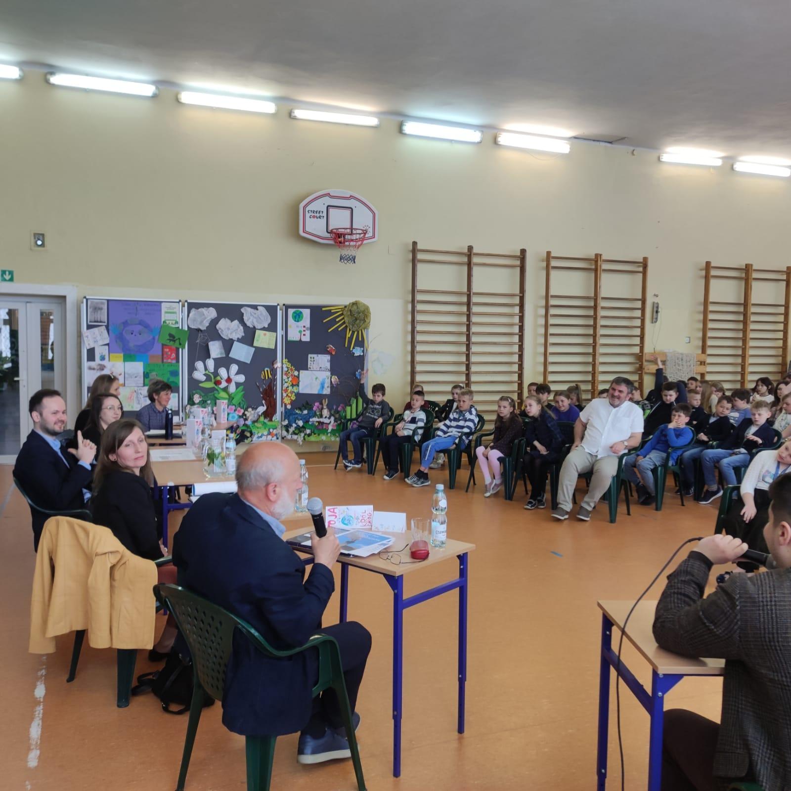 Debata o smofu - sala wypełniona dziećmi, a na środku stół z zaproszonymi ekspertami.
