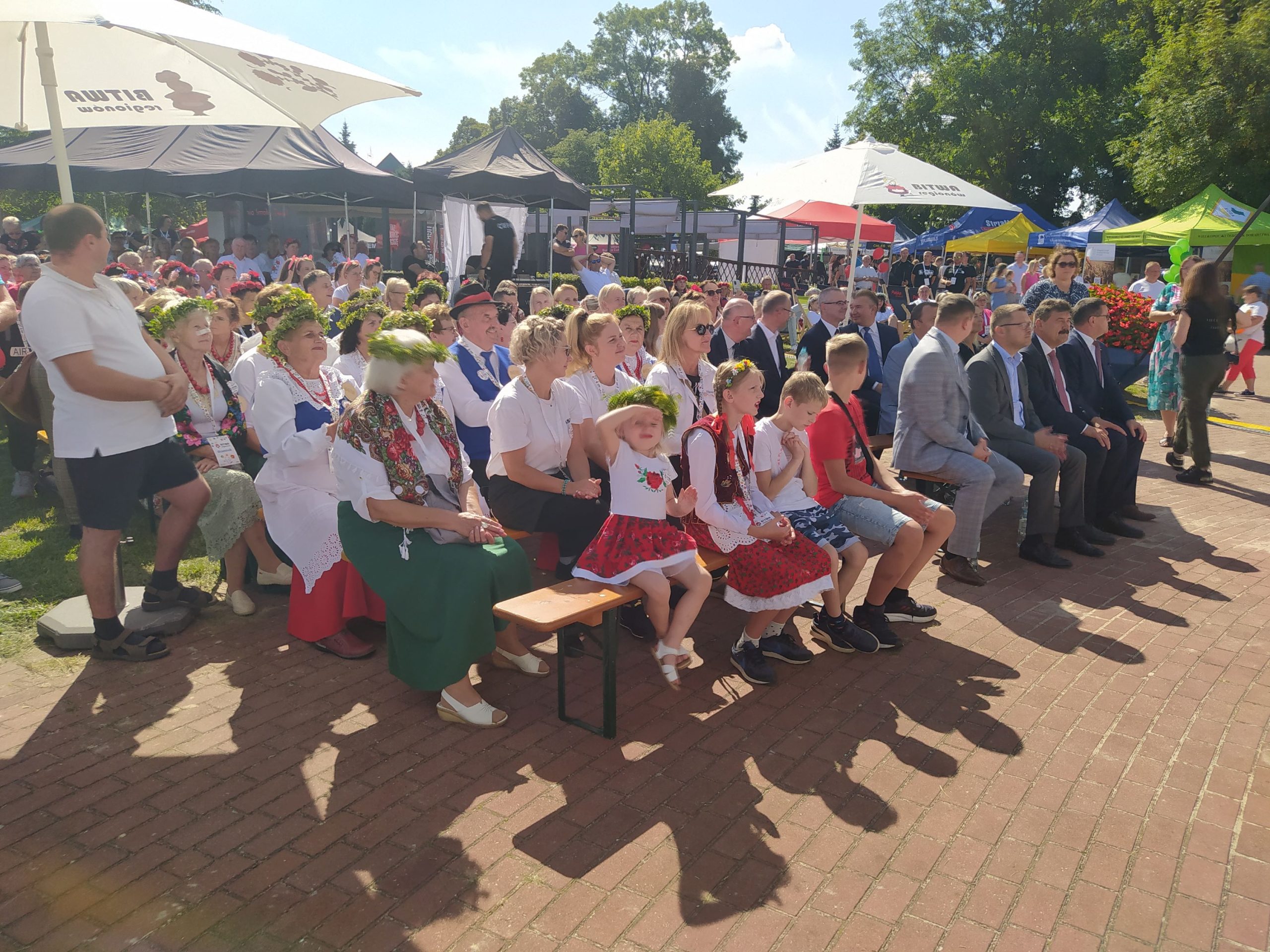 Uczestnicy festynu siedzą  przed sceną w rzędach krzeseł 