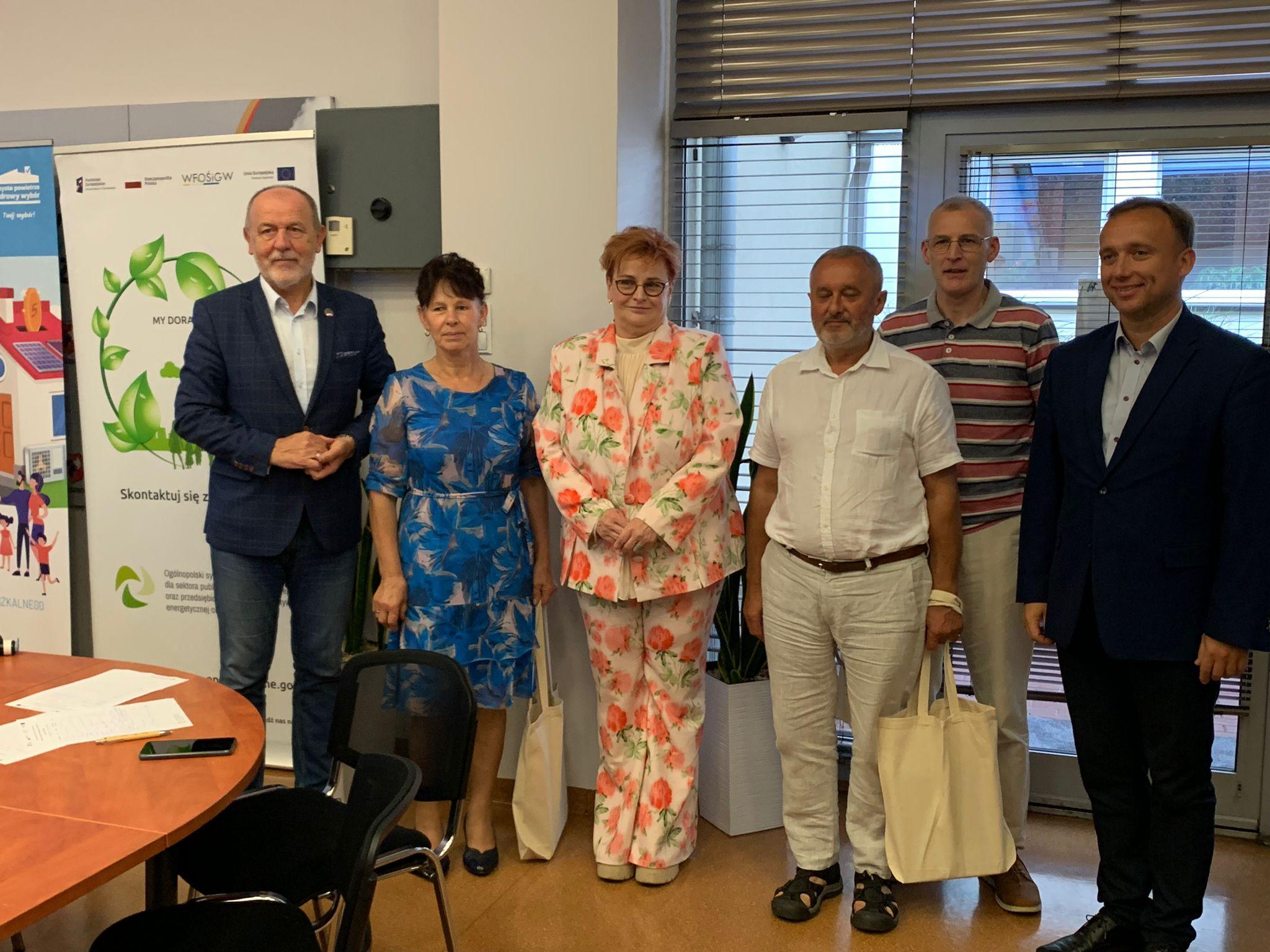 Uczestnicy szkolenia siedzą przy stołach i słuchają.