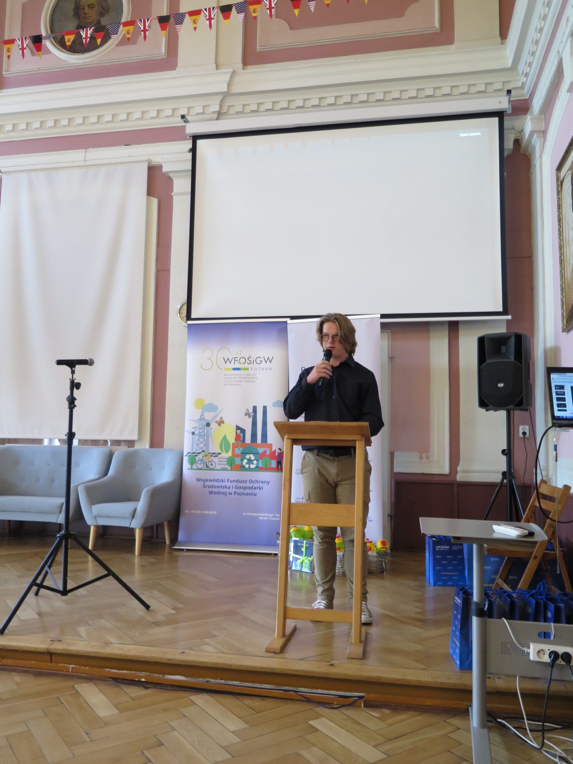 Jedna osoba stoi na scenie i przemawia.