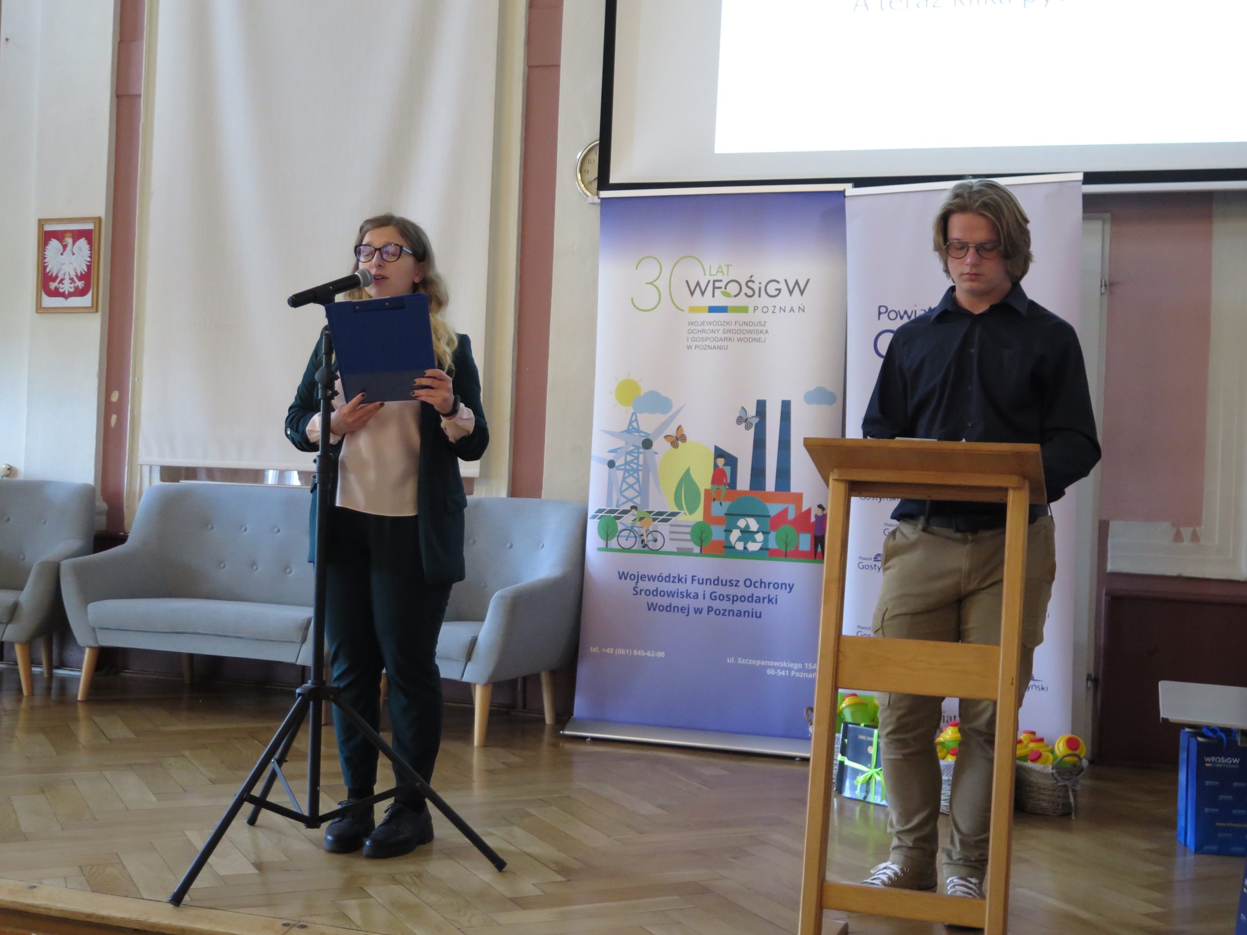 2 osoby stoją na scenie i mówią.