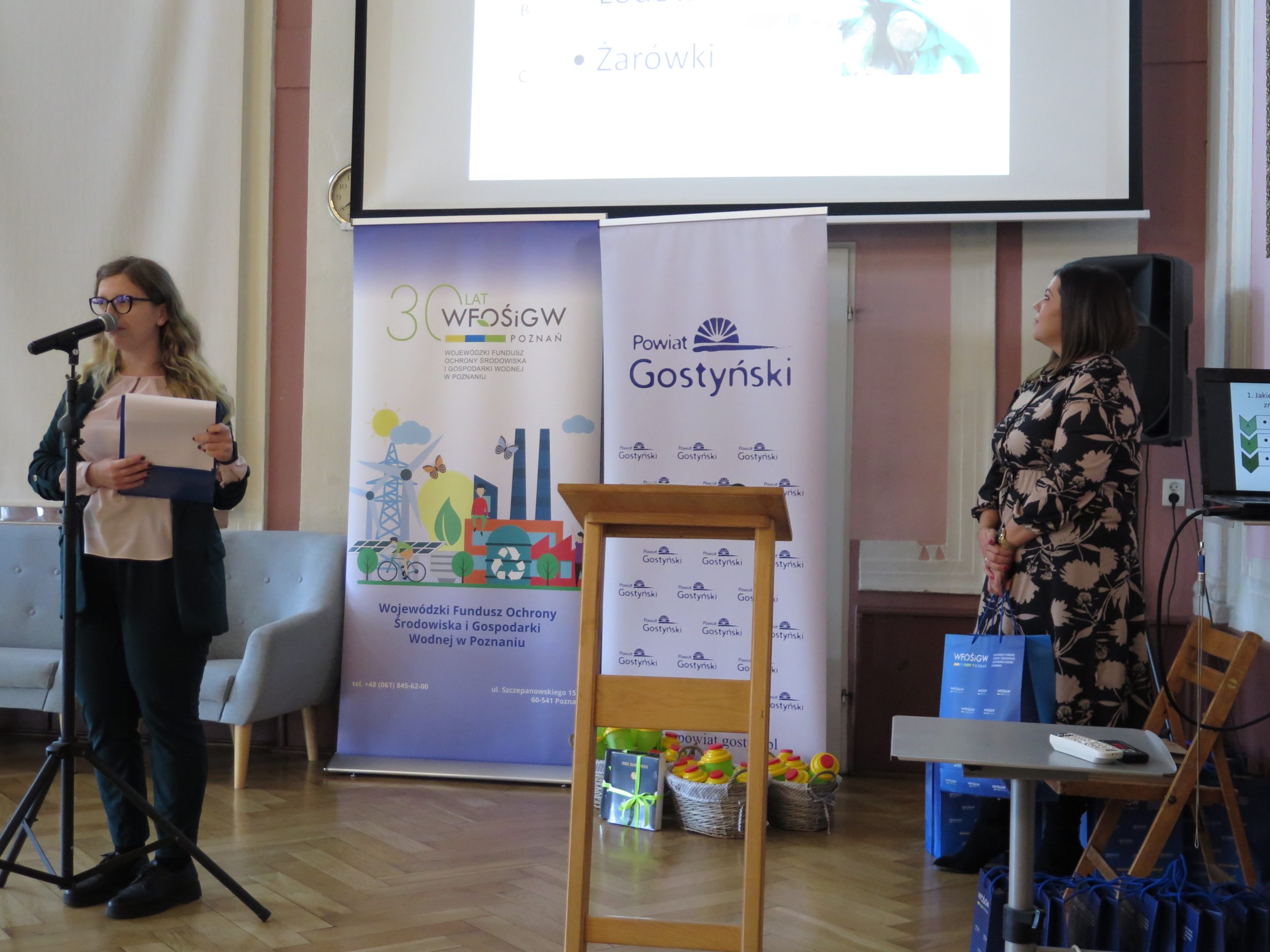 2 osoby stoją na scenie, jedna mówi.