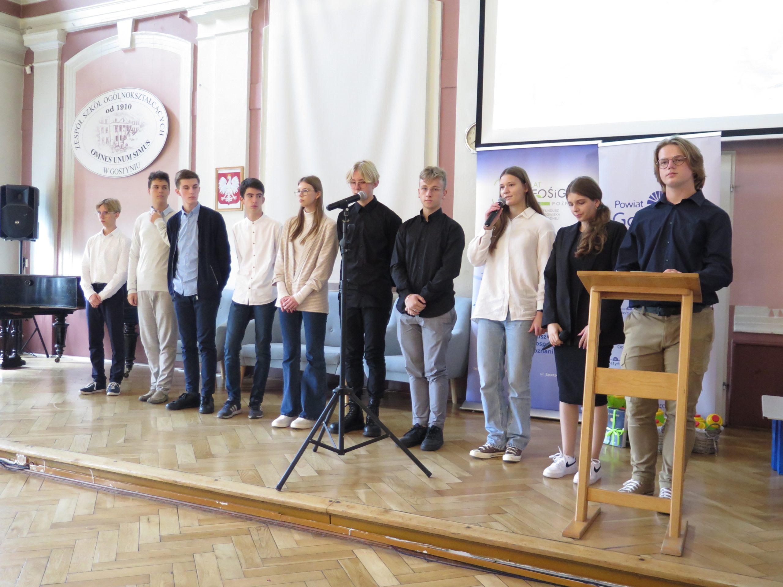 Grupa uczniów stoi na scenie.