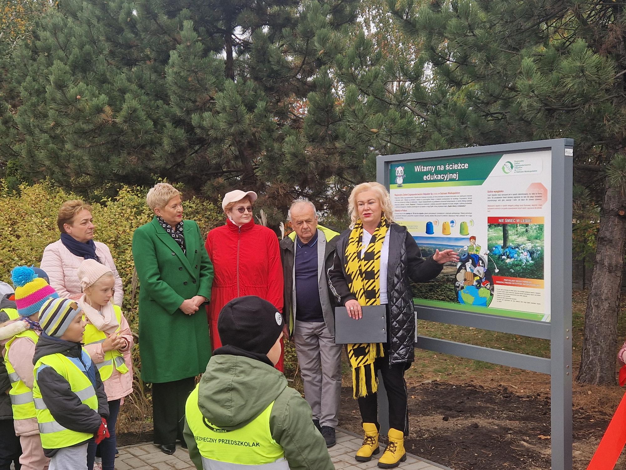 Grupa osób stojaca na początku ścieżki edukacyjnej, dorosli oraz dzieci.