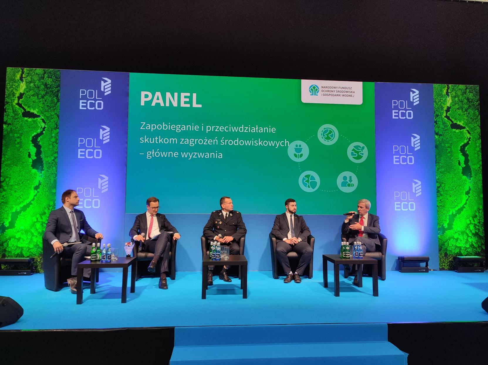 5 osób siedzi na fotelach na scenie i debatuje