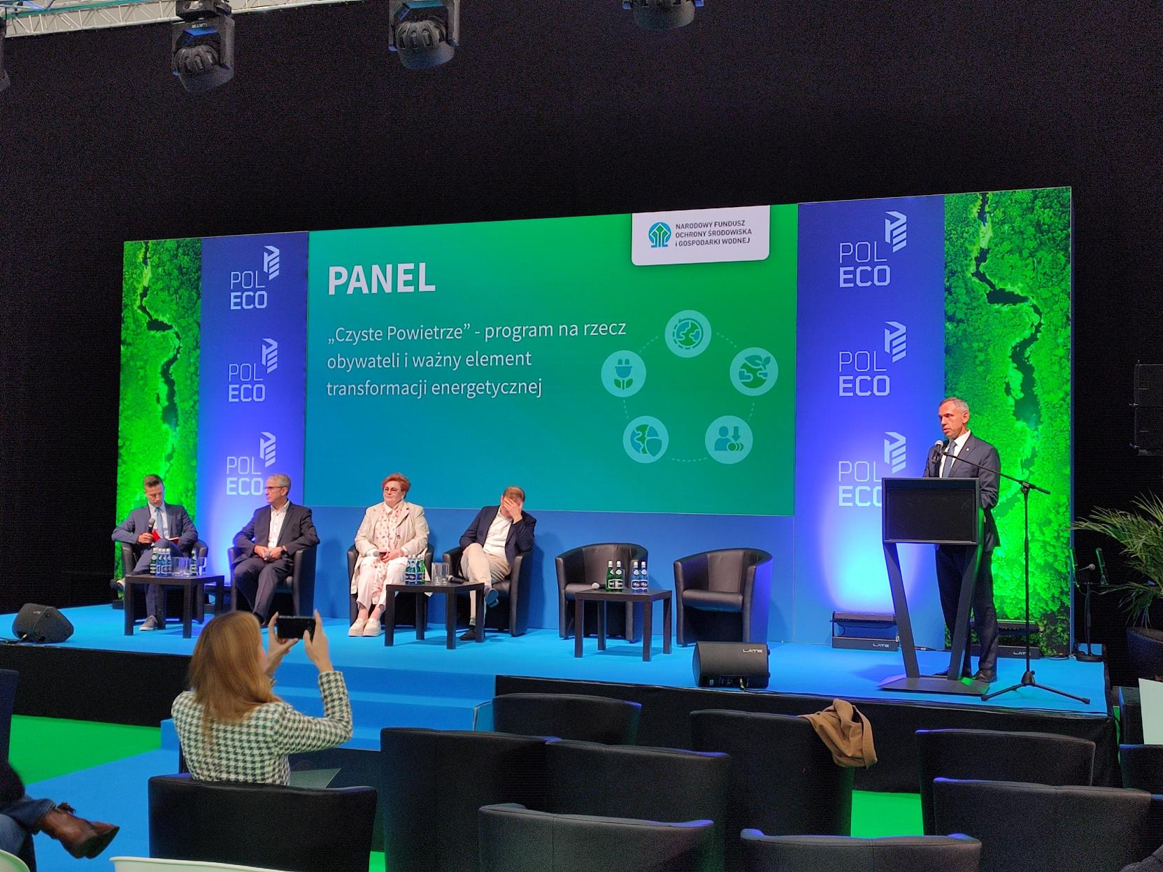 5 osób siedzi na fotelach na scenie i debatuje