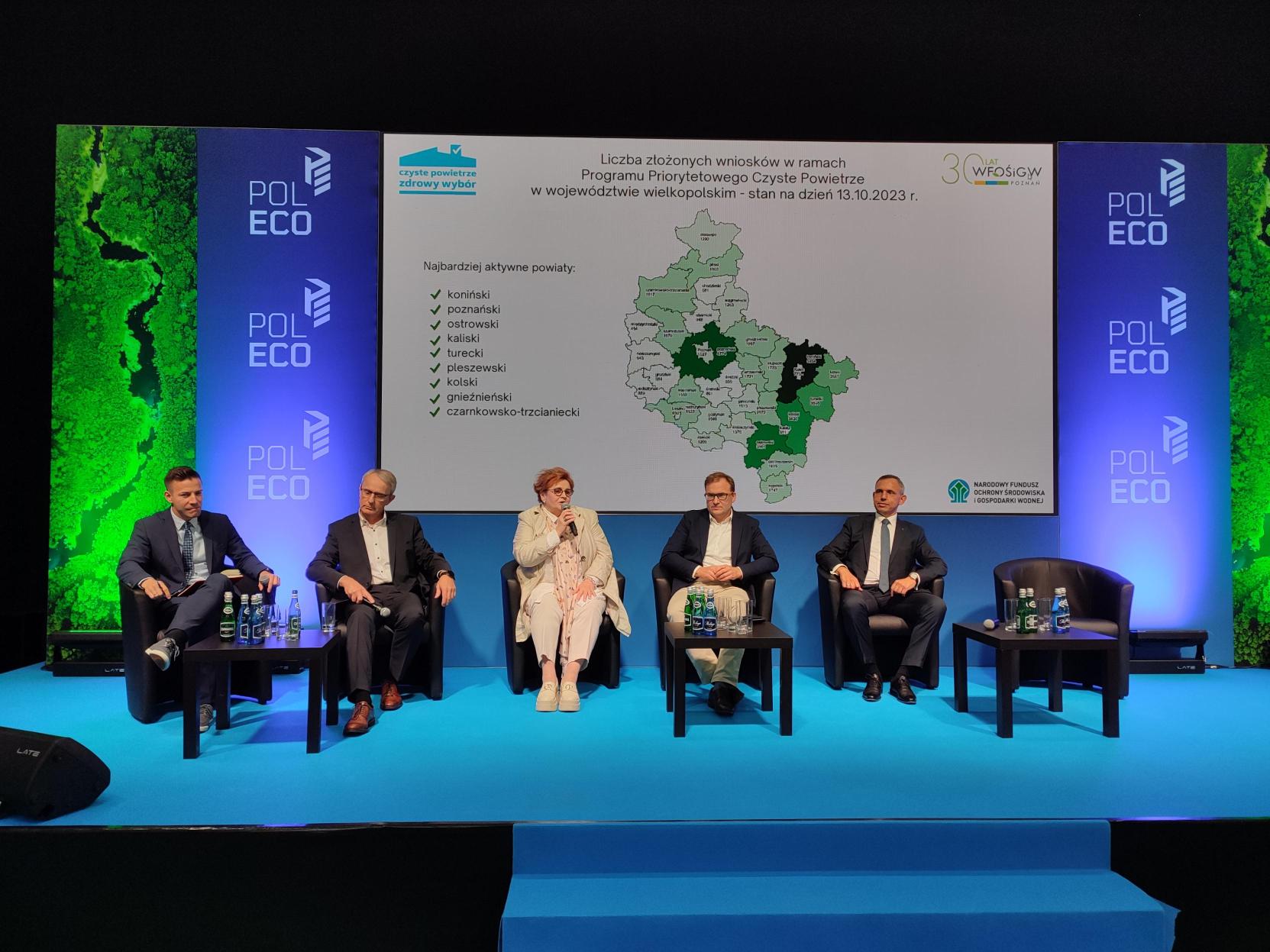 5 osób siedzi na fotelach na scenie i debatuje