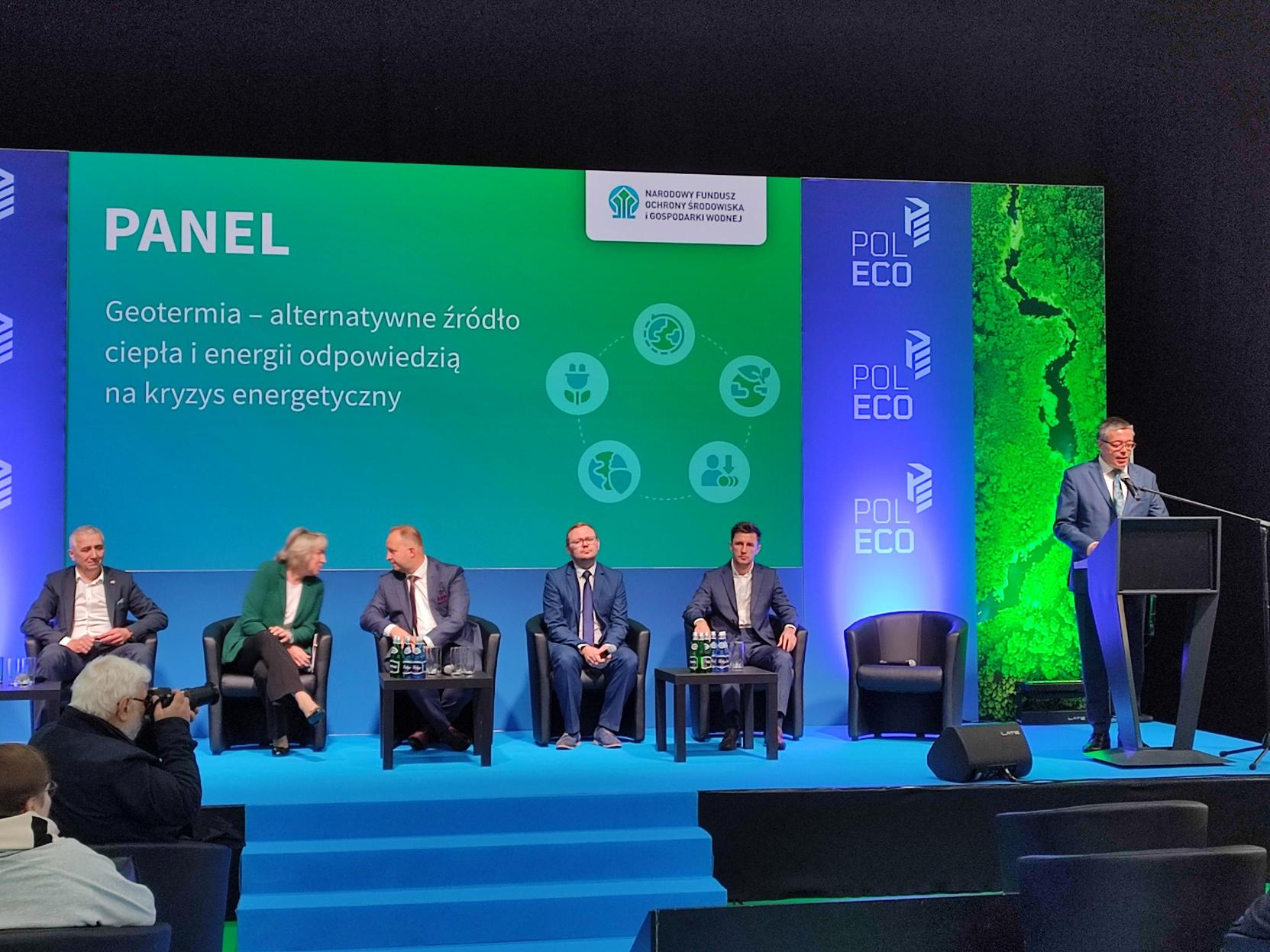 5 osób siedzi na fotelach na scenie i debatuje