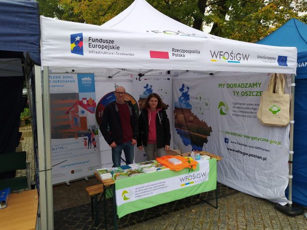 2osoby stoją pod namiotem wystawienniczym podczas pikniku