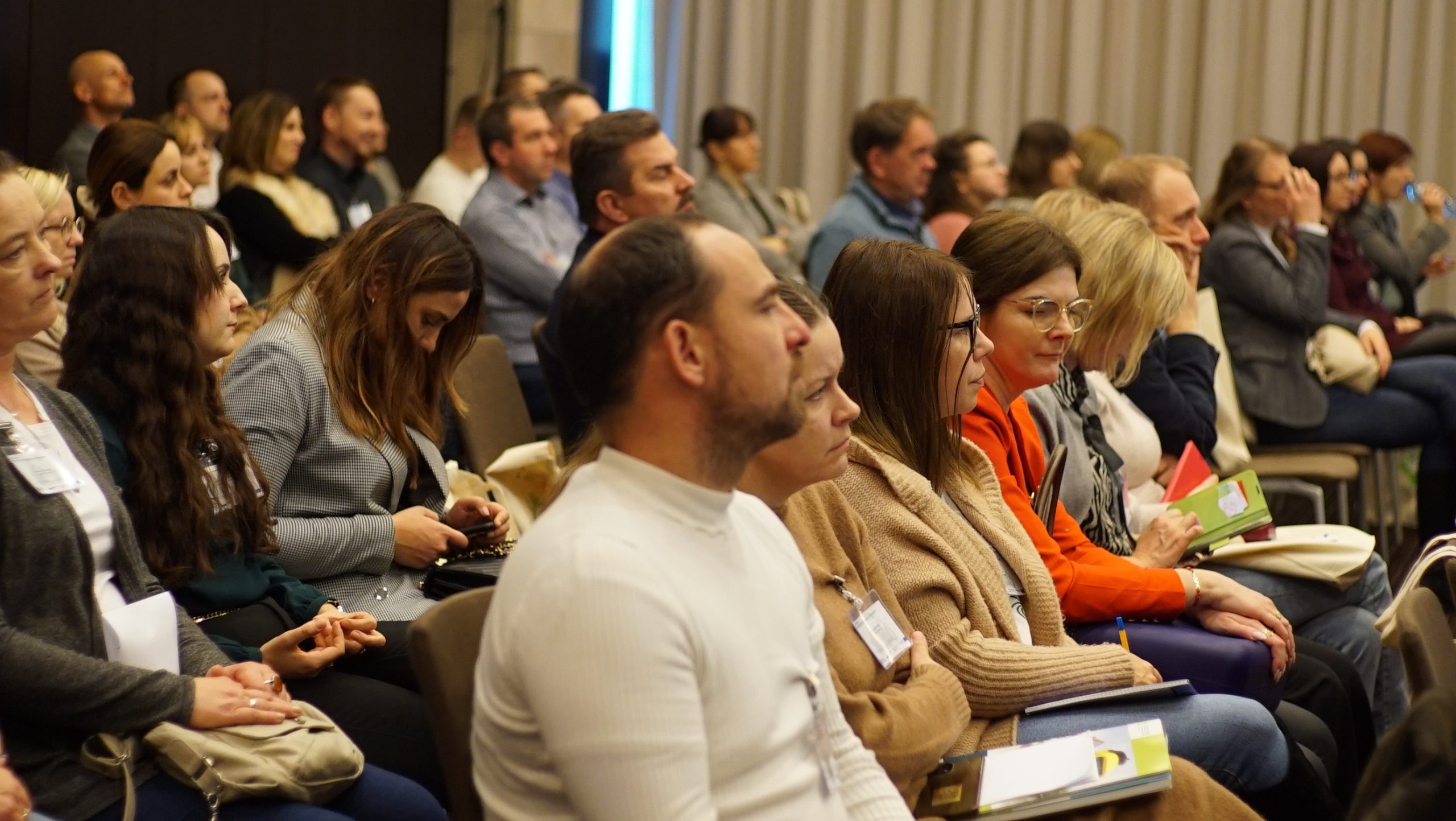 uczestnicy konferencji siedzą i słuchają.